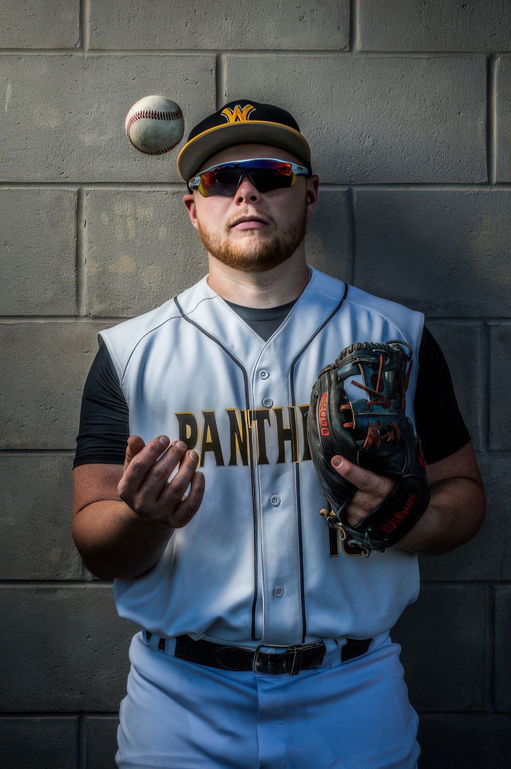 Baseball player demonstrates ball grip techniques against concrete wall.