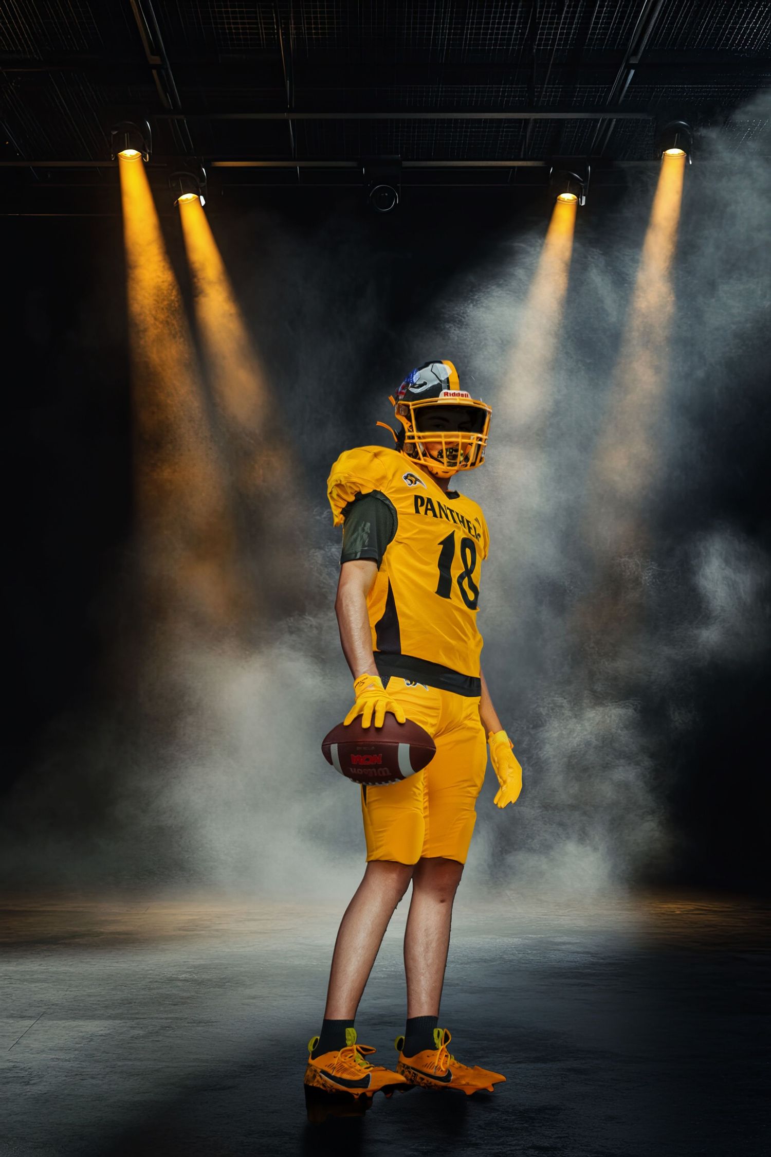 American football player in yellow uniform holding a ball under dramatic spotlights with smoke effects on dark stage.