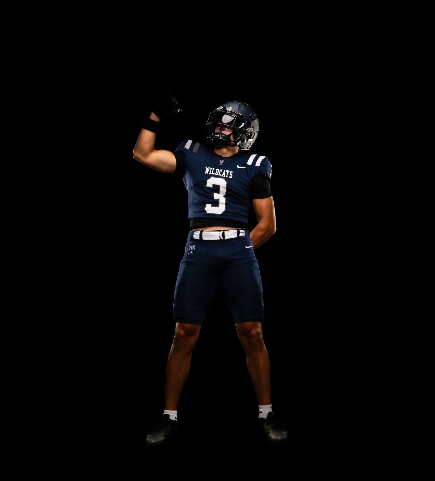 Football player wearing navy Wildcats jersey number 3 poses dynamically against black background.
