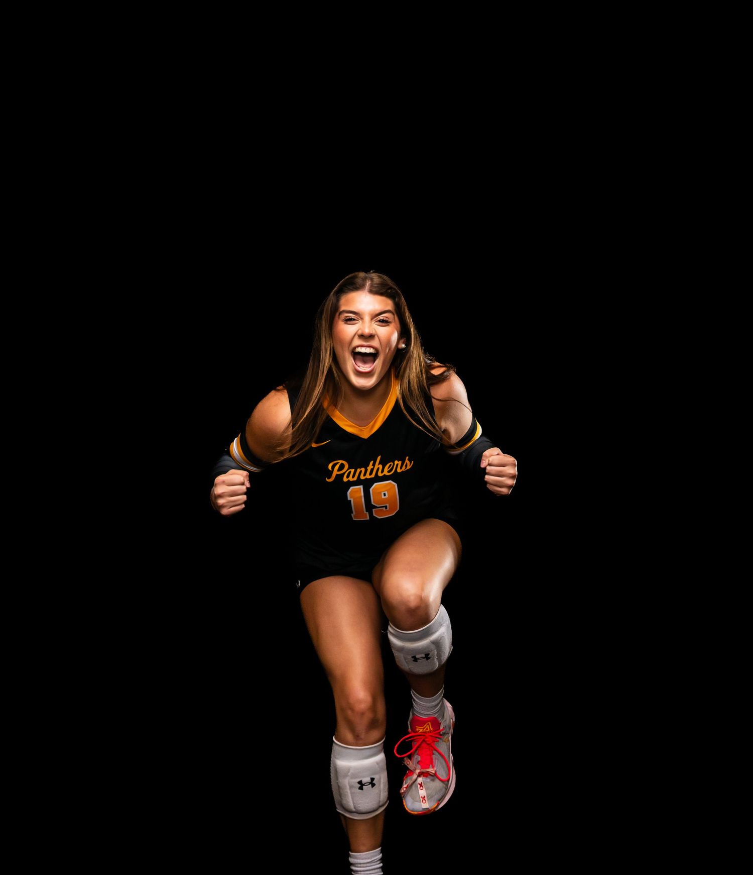Energetic Panthers #19 volleyball player celebrates in black and gold jersey during team photo session.