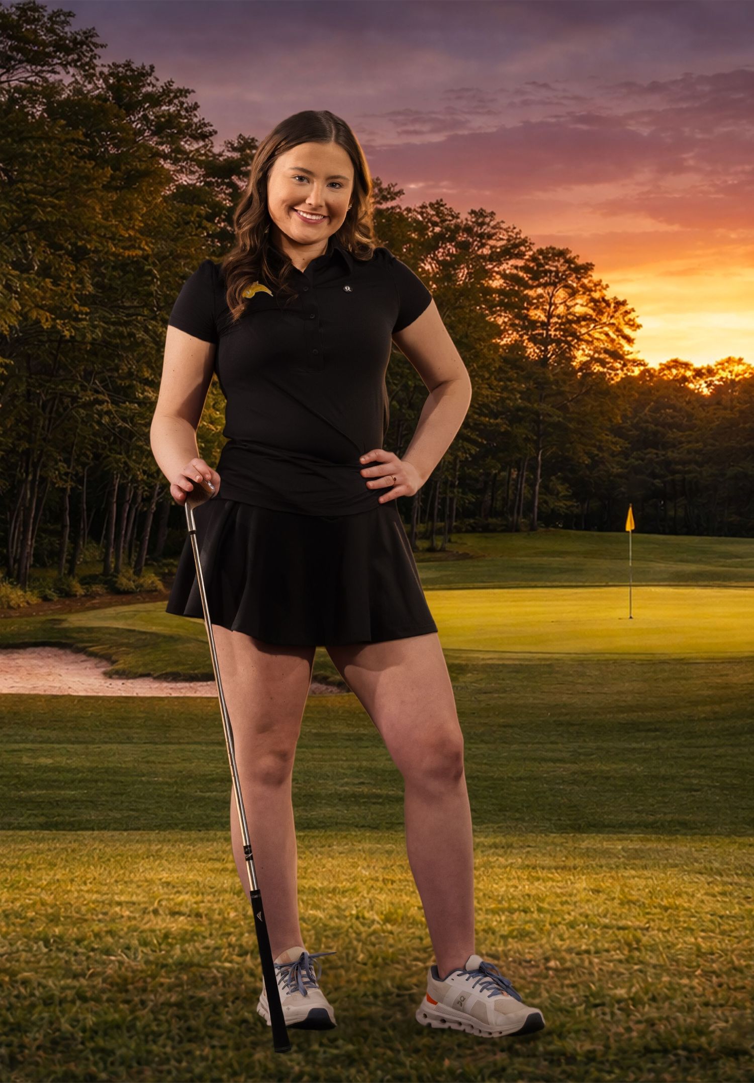 A golfer in black attire poses on a golf course during a vibrant sunset with golden light filtering through trees.