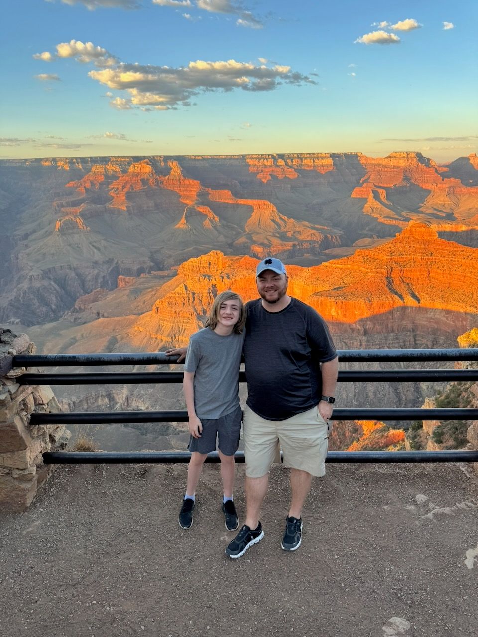 Stunning sunset view of the Grand Canyon with orange-lit cliffs and viewing platform.