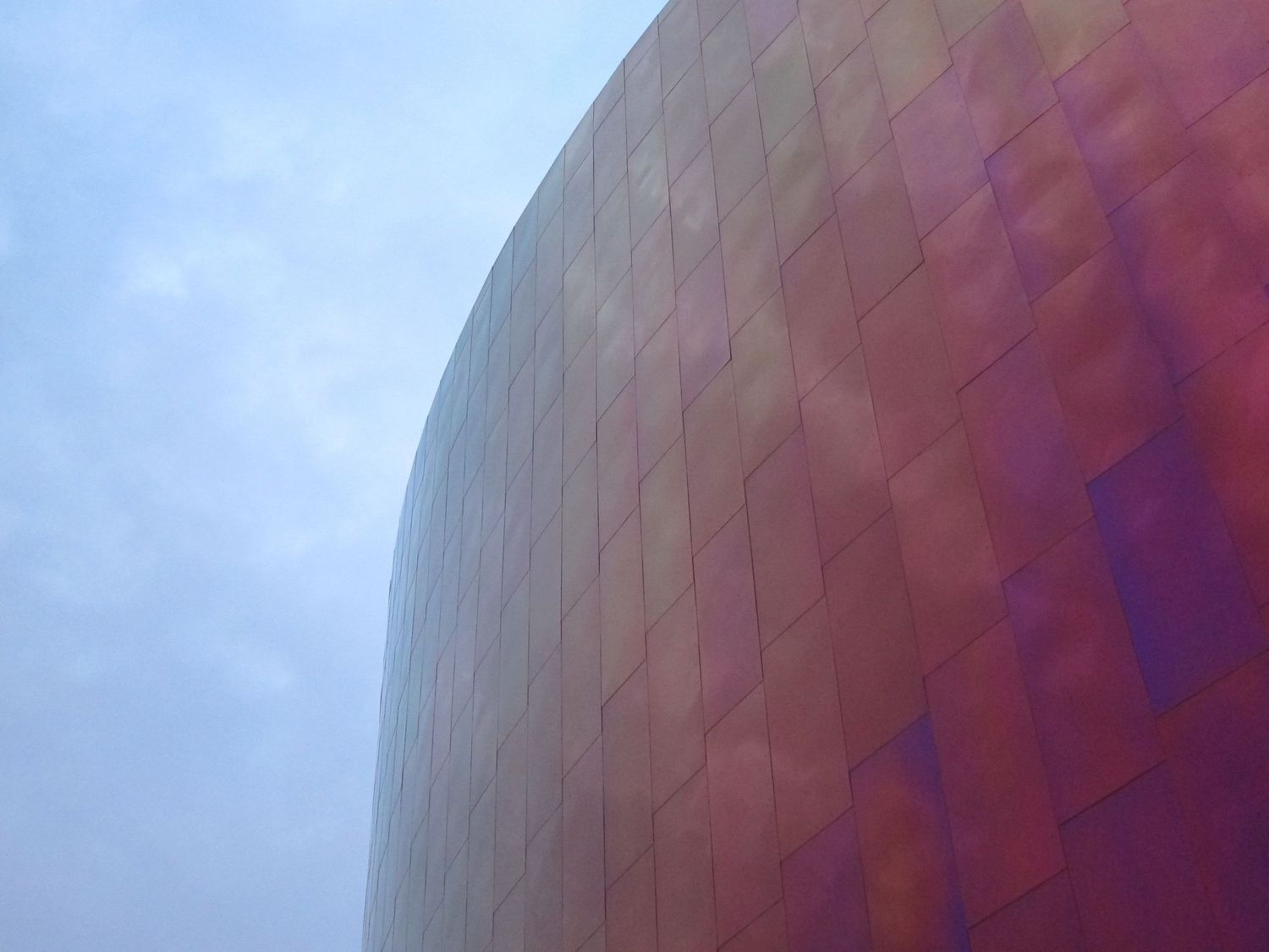 Abstract architectural detail with curved metallic surfaces reflecting purple and blue tones.