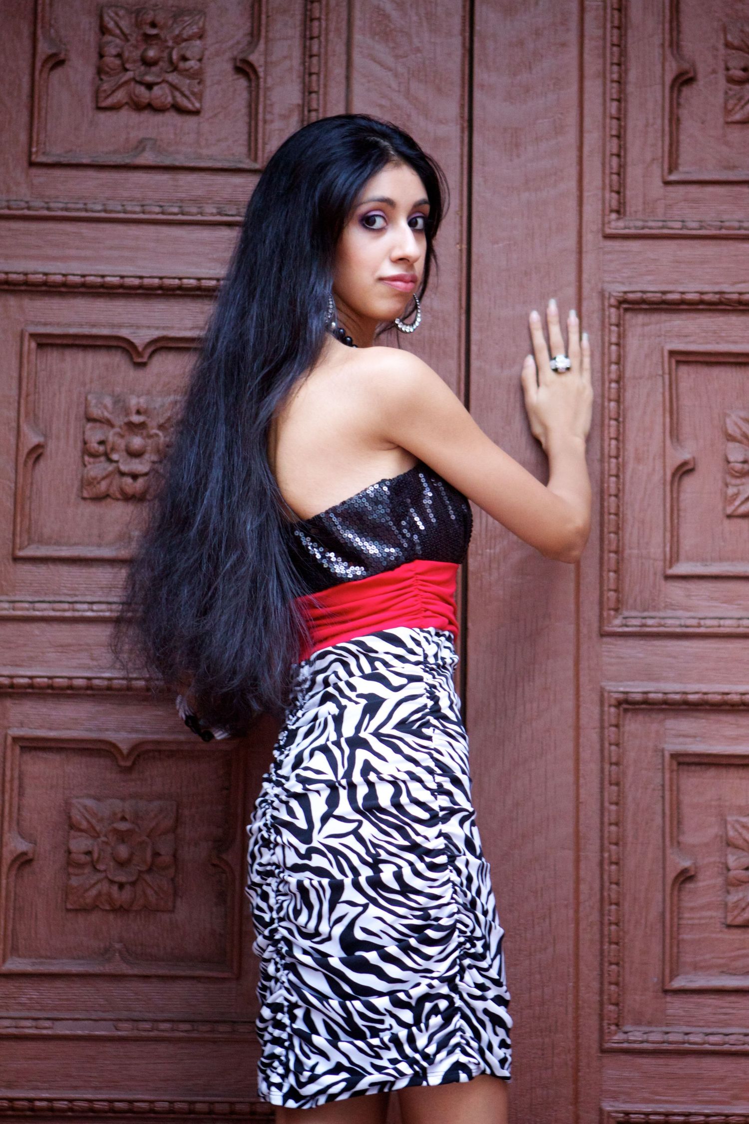 Fashion portrait featuring a zebra print dress against an ornate brown door.