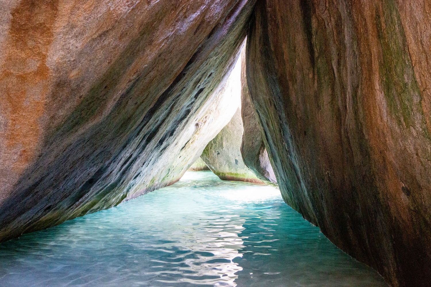 Dramatic rock canyon walls with sunlight streaming through creating a natural tunnel effect.