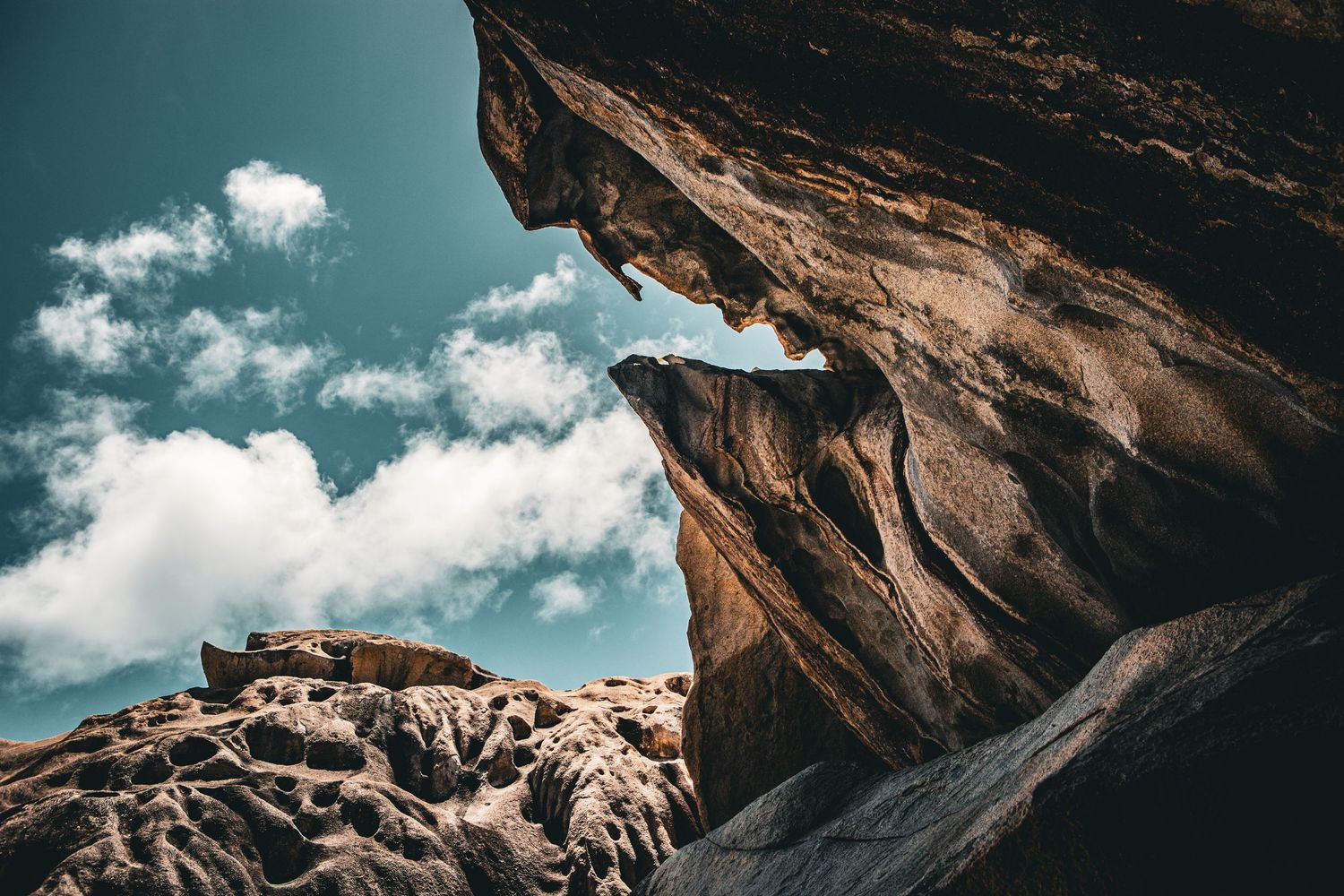 Majestic rock formations under a blue sky with white clouds framing the natural arch.