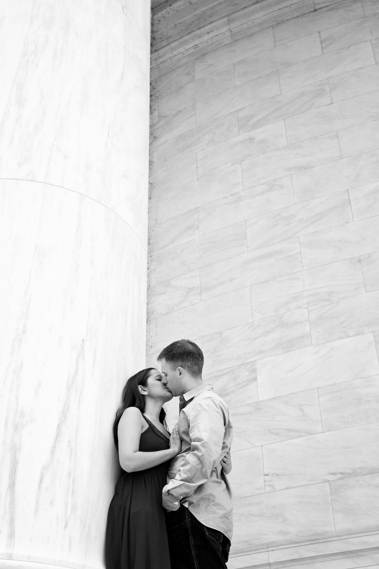 Black and white portrait of couple in romantic pose against marble wall.