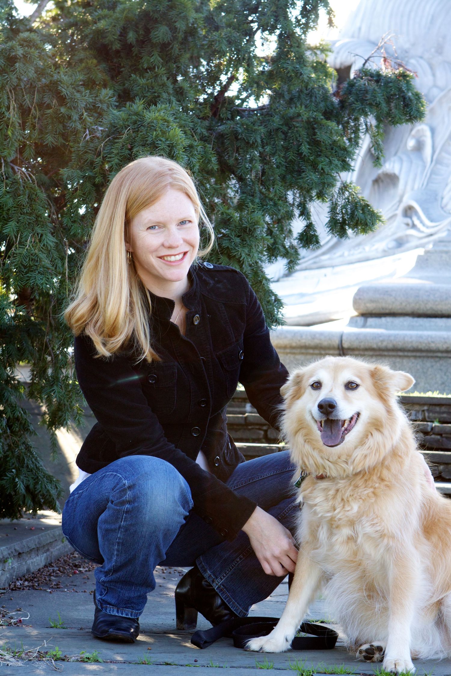 Casual outdoor portrait with happy golden retriever by statue.