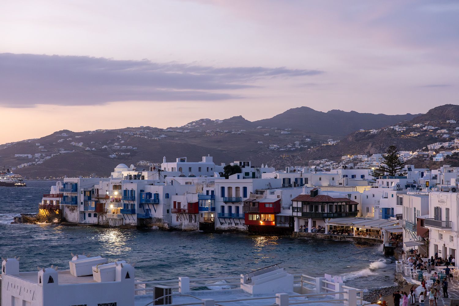 Seaside view of Little Venice in Mykonos with traditional white buildings at twilight.