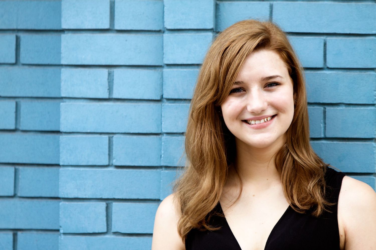 Portrait series against blue brick wall background showcasing casual expressions.