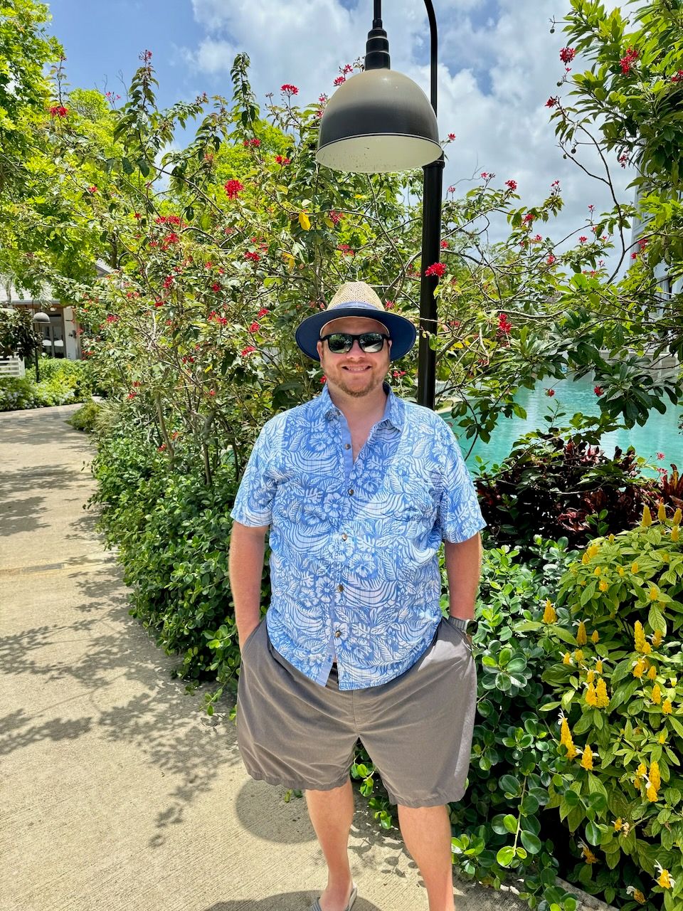 Tropical garden setting with flowering plants and lamp posts.