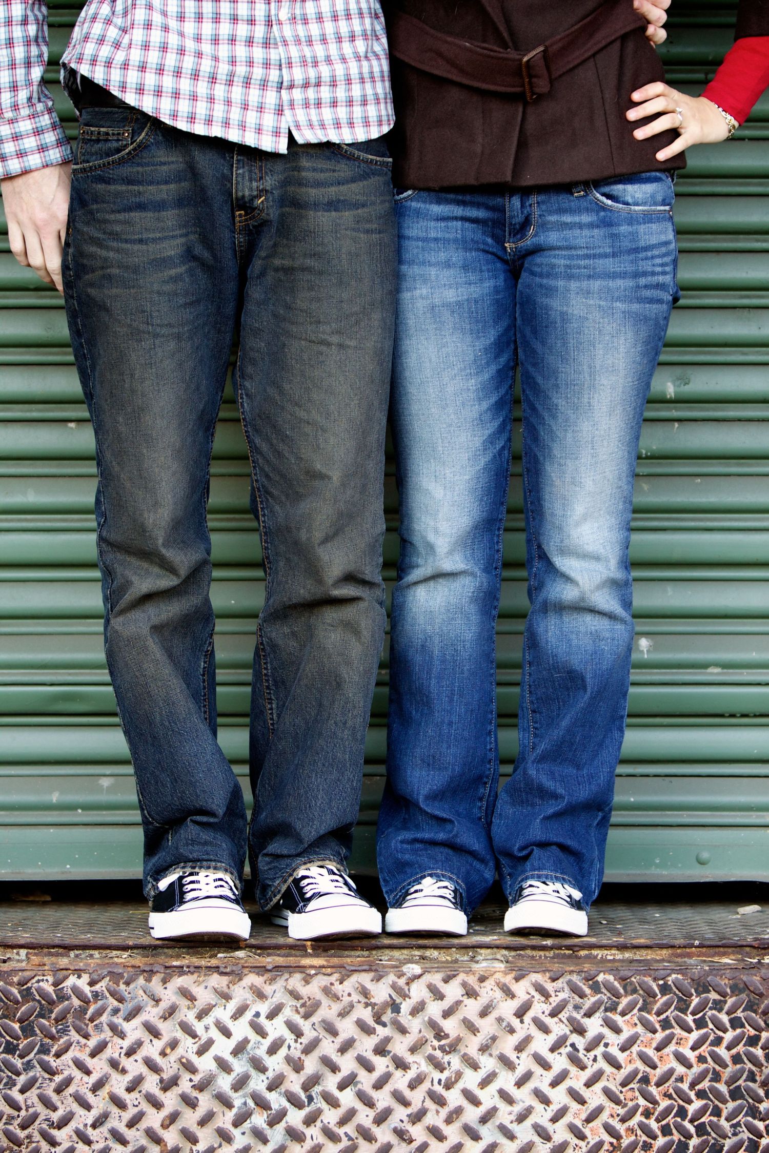 Cropped photo of legs and feet showing couples wearing jeans and sneakers on metal surface.