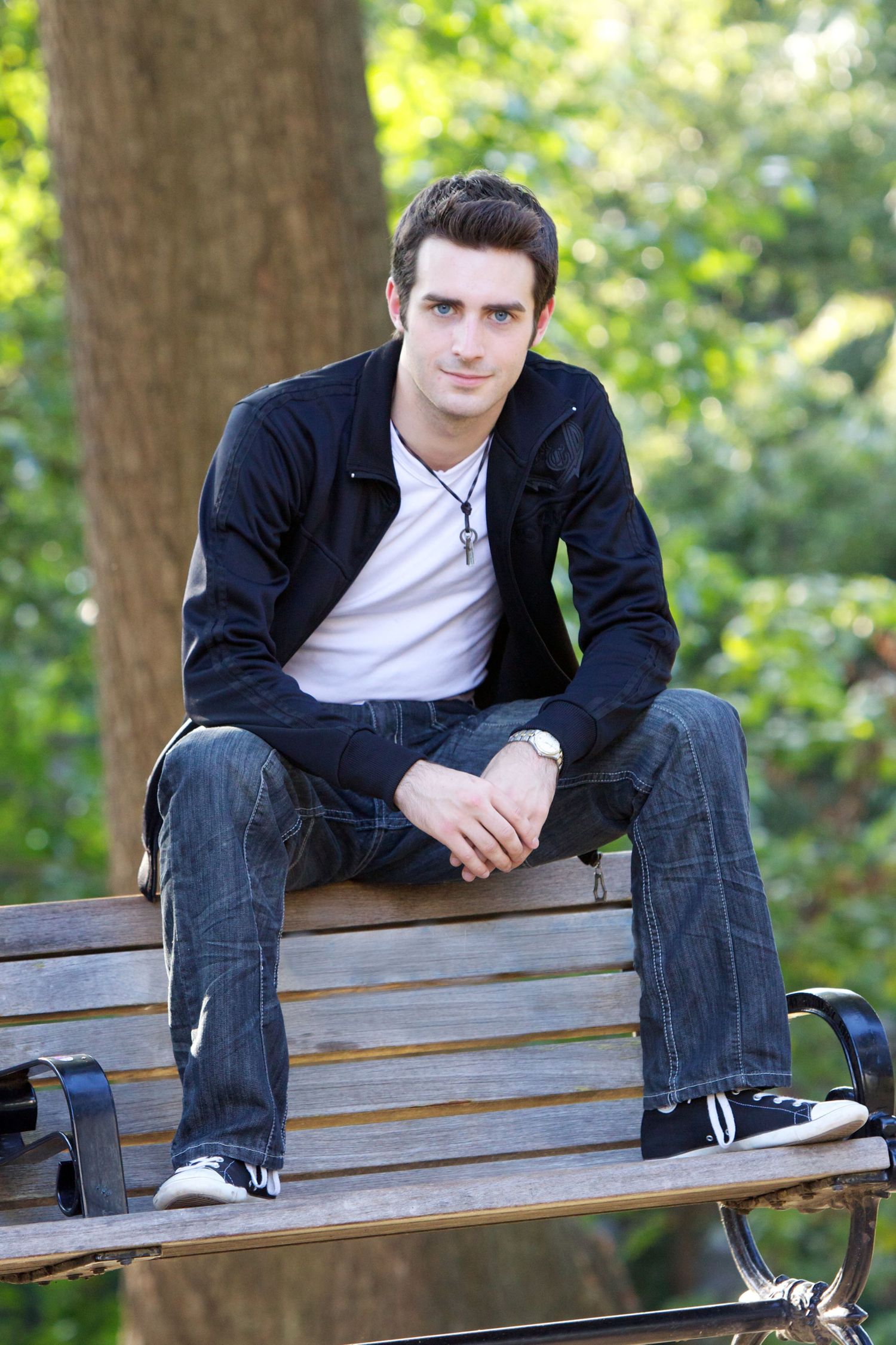 A series of casual outdoor portraits showing someone sitting on a wooden park bench wearing jeans and a dark jacket.