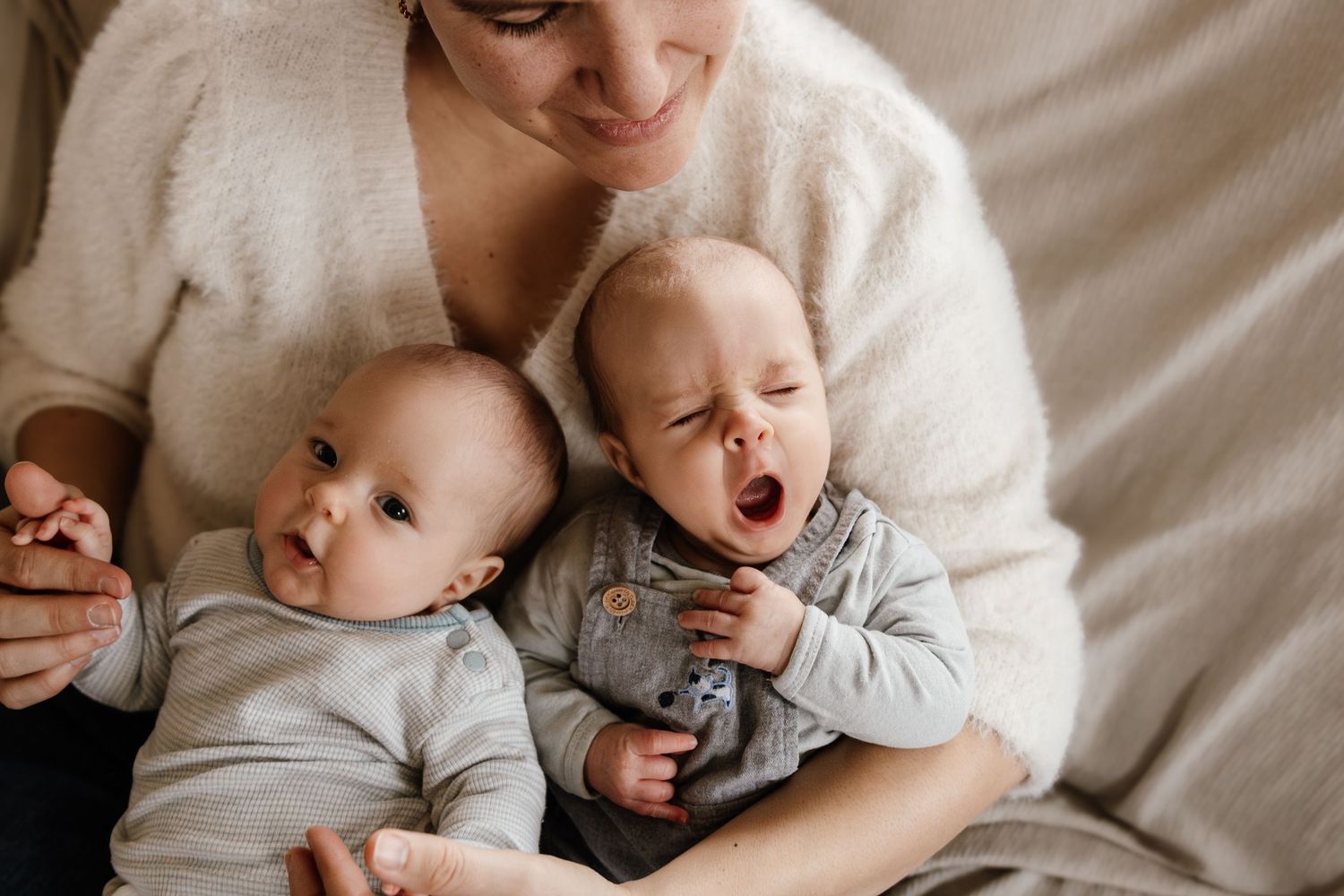Sweet candid moments of a family snuggling together on white bedding.