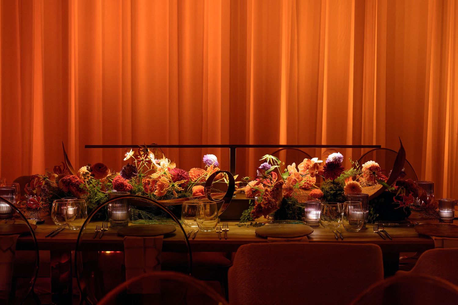 Banquet tables with autumn-themed decor against warm orange curtain backdrop.
