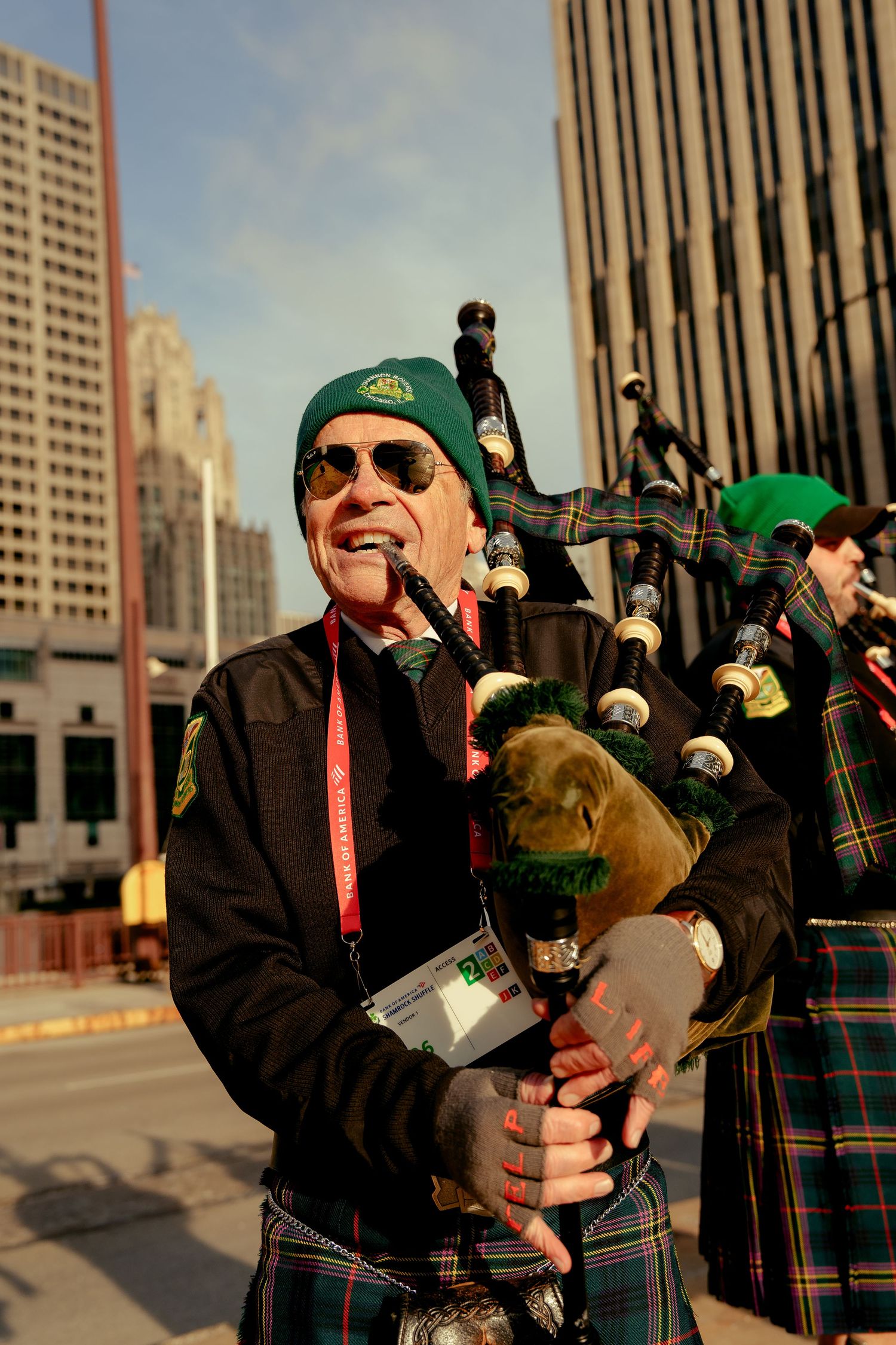 Bagpiper in green beret and tartan kilt performs at St. Patrick's Day parade in downtown Chicago.