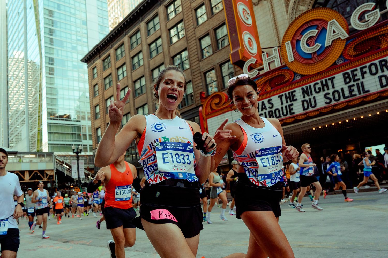 Group of enthusiastic marathon runners passing by the Chicago Theatre.