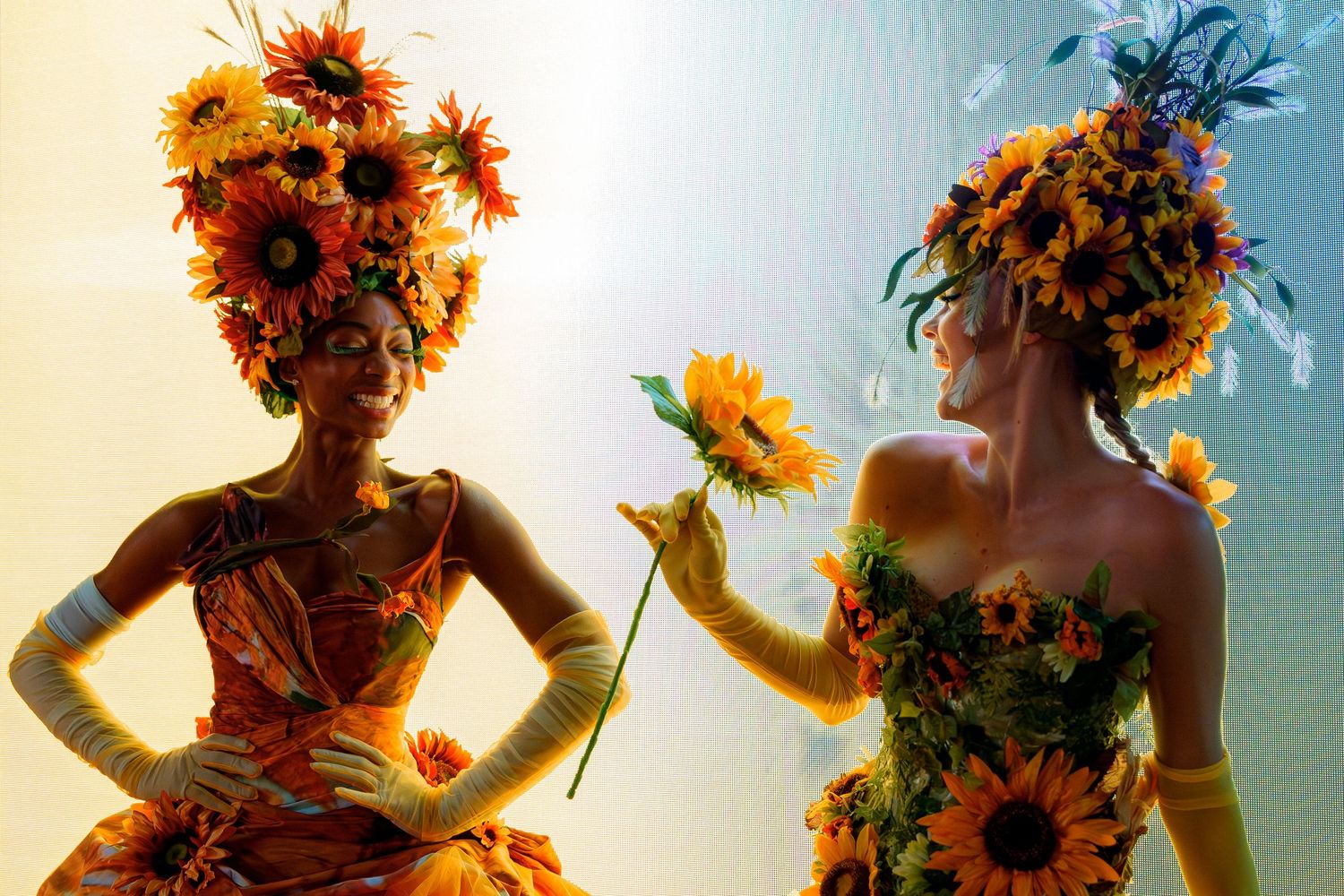 Artistic silhouettes adorned with floral headpieces and dramatic lighting create a whimsical display.