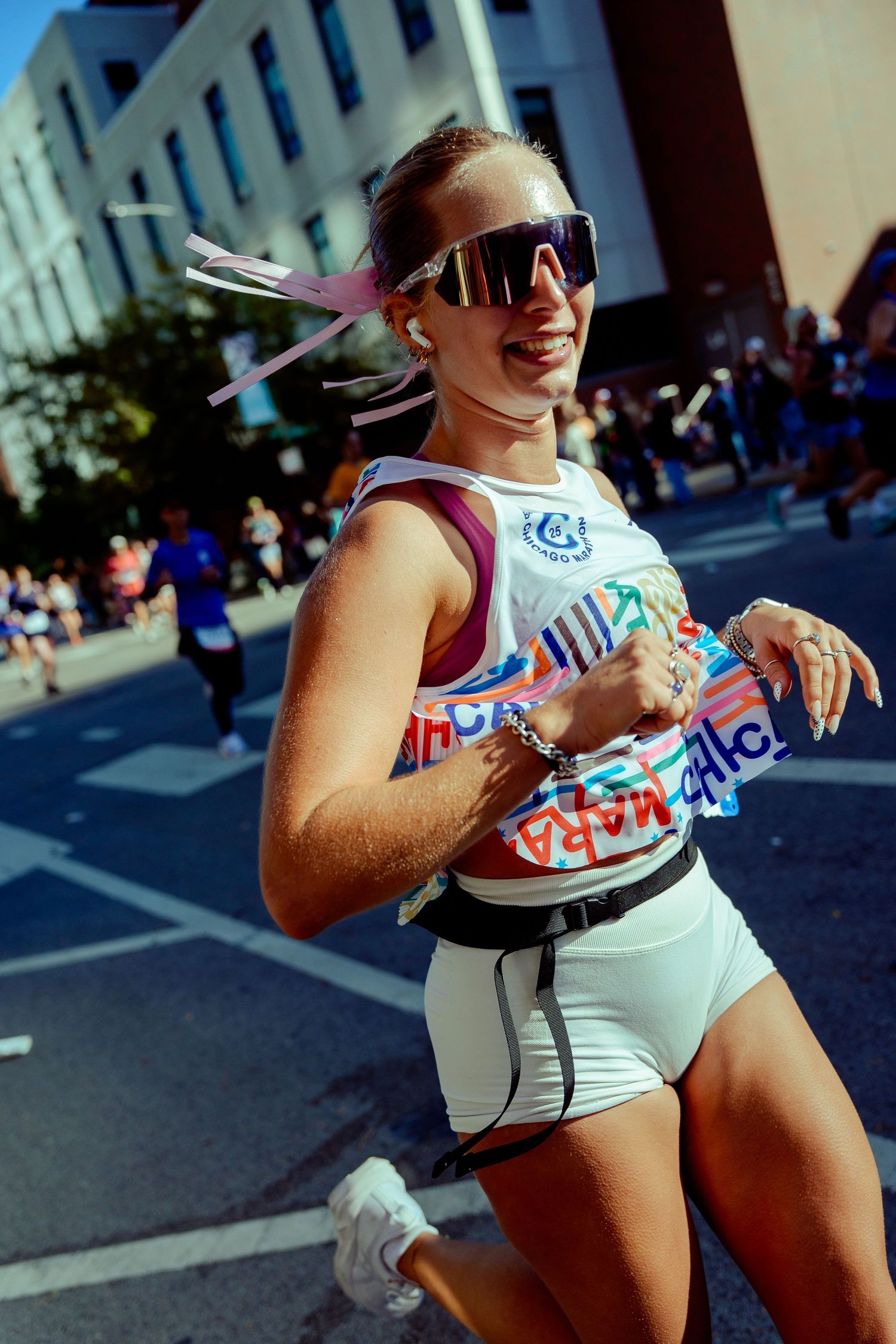 Runner in white athletic wear smiling during a city marathon race.