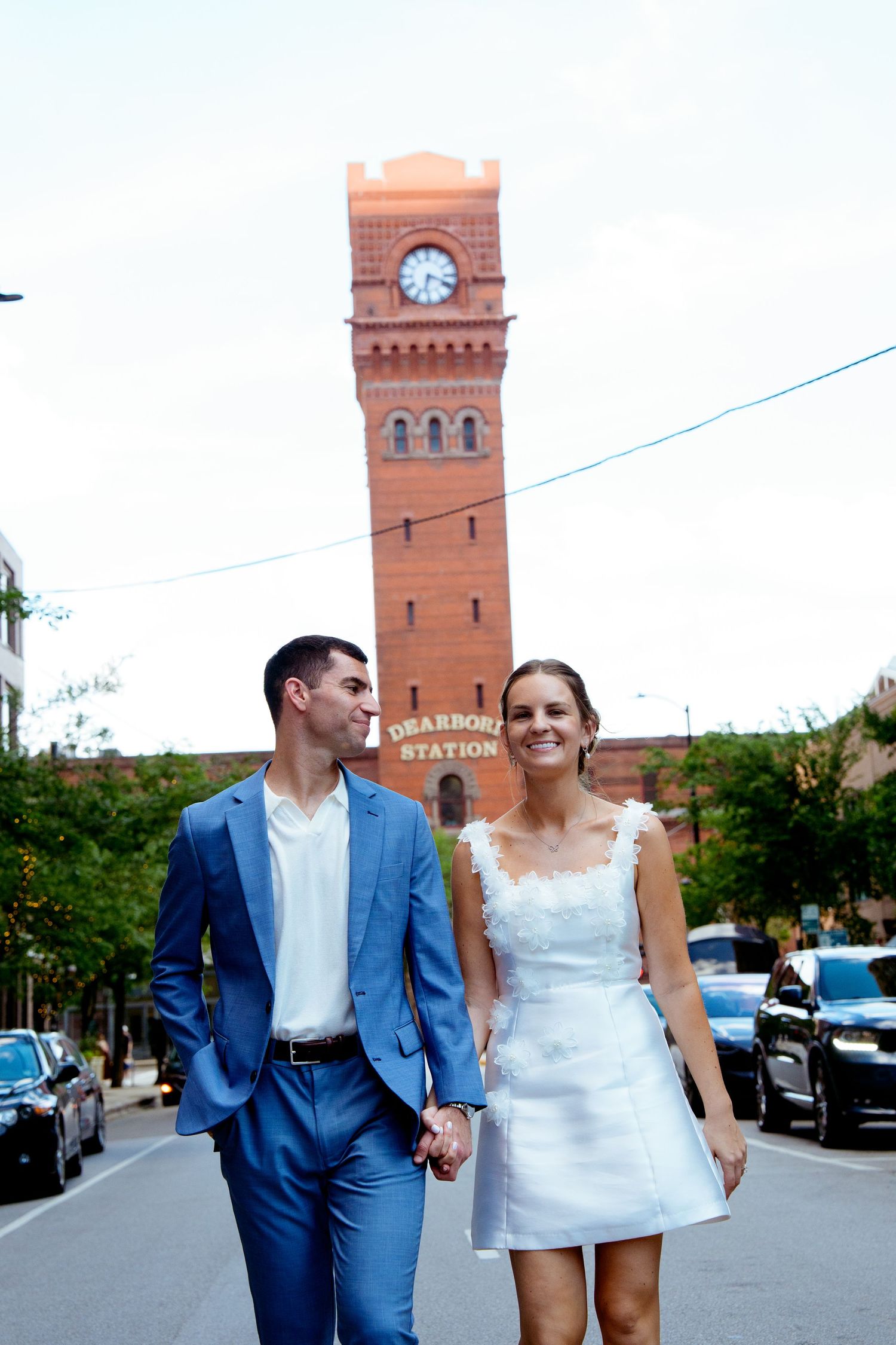 Couple walking together near a historic brick clock tower building.