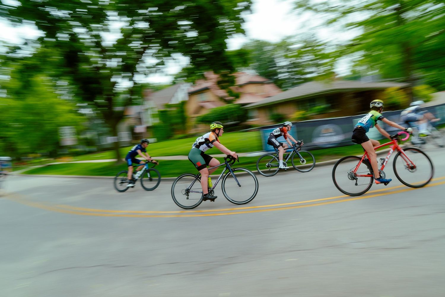 Motion-blurred shot of cyclists racing through a residential neighborhood.