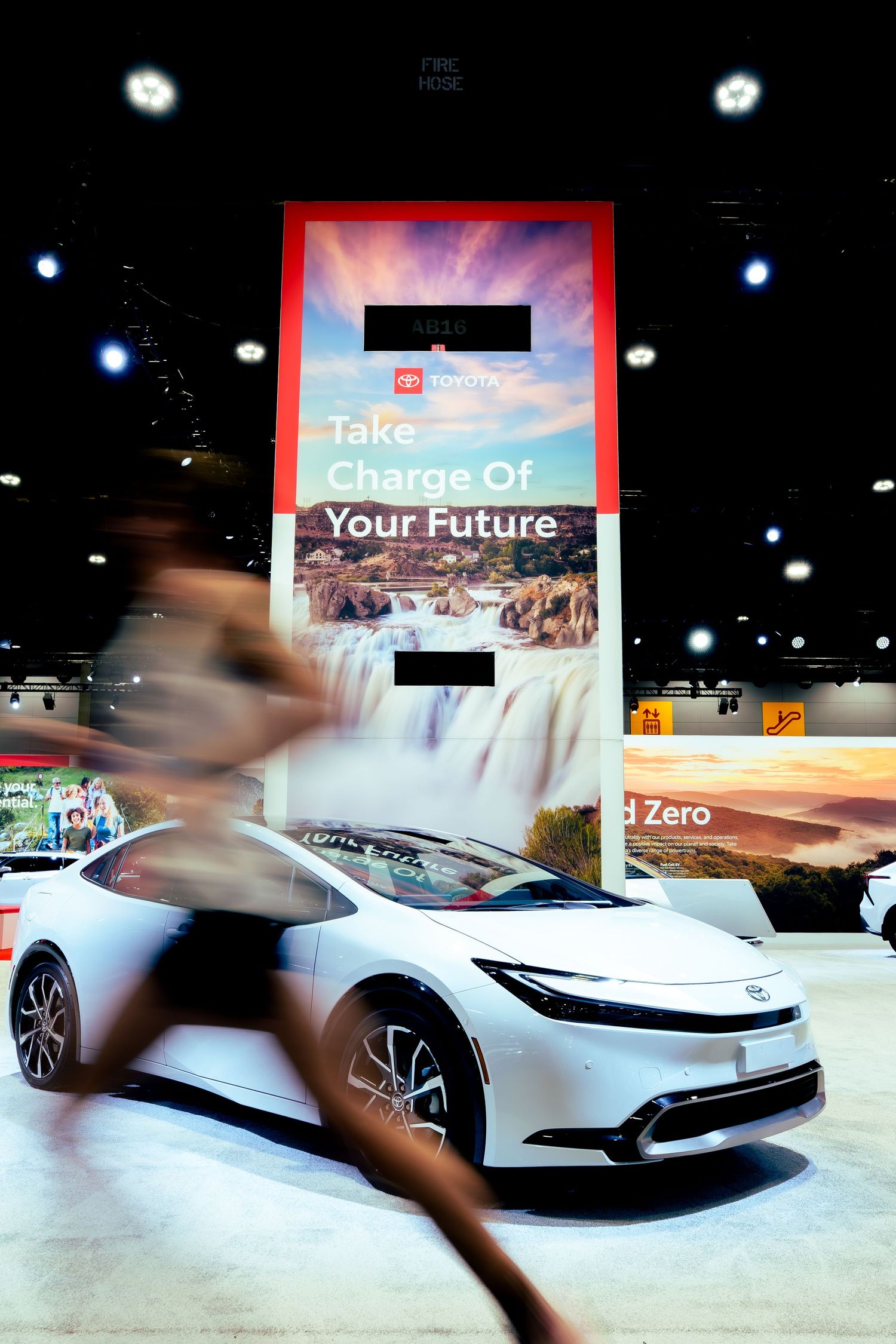 Modern white electric vehicles on display with illuminated marketing signs in showroom.