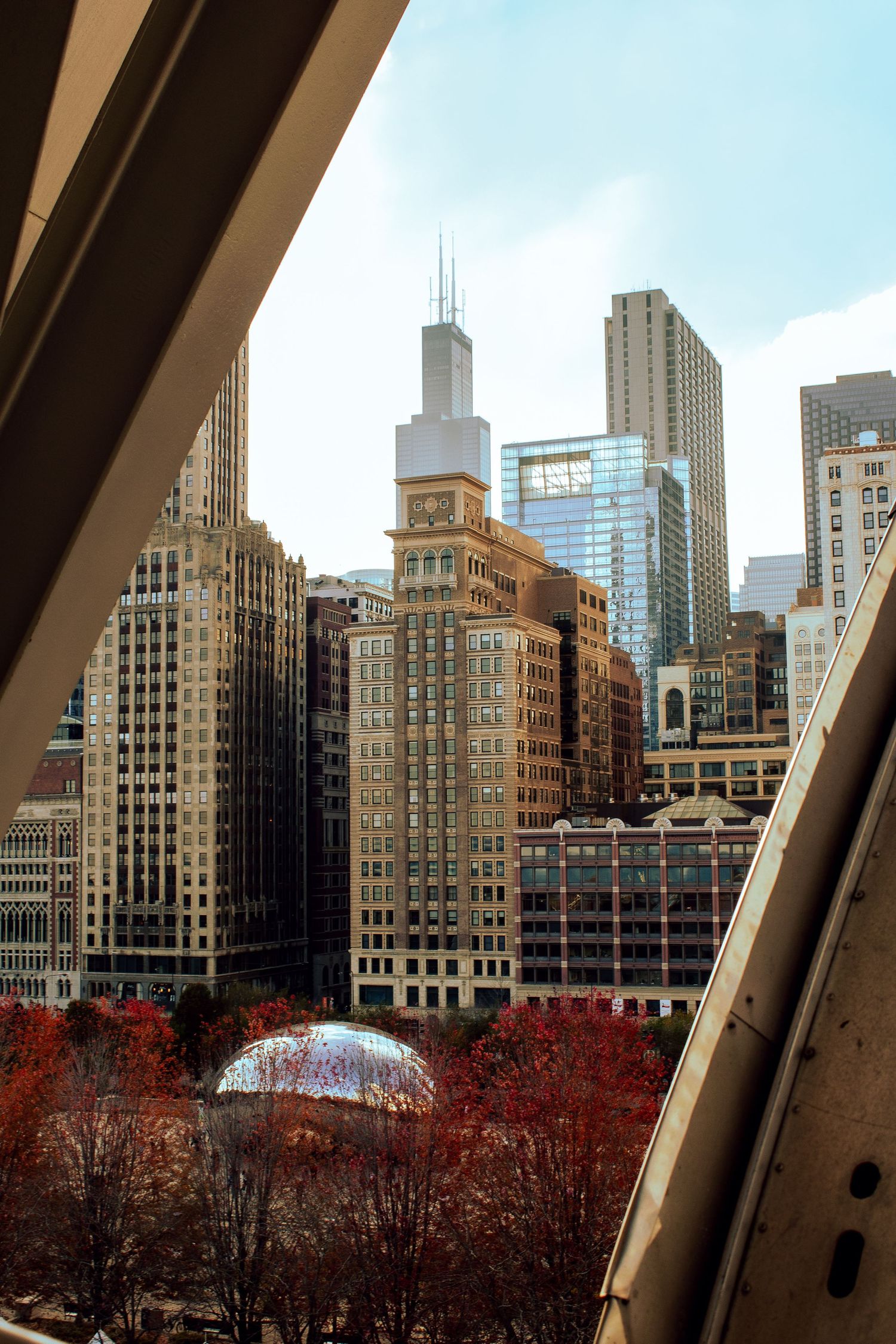Chicago skyline with Willis Tower and fall foliage viewed through architectural framing.