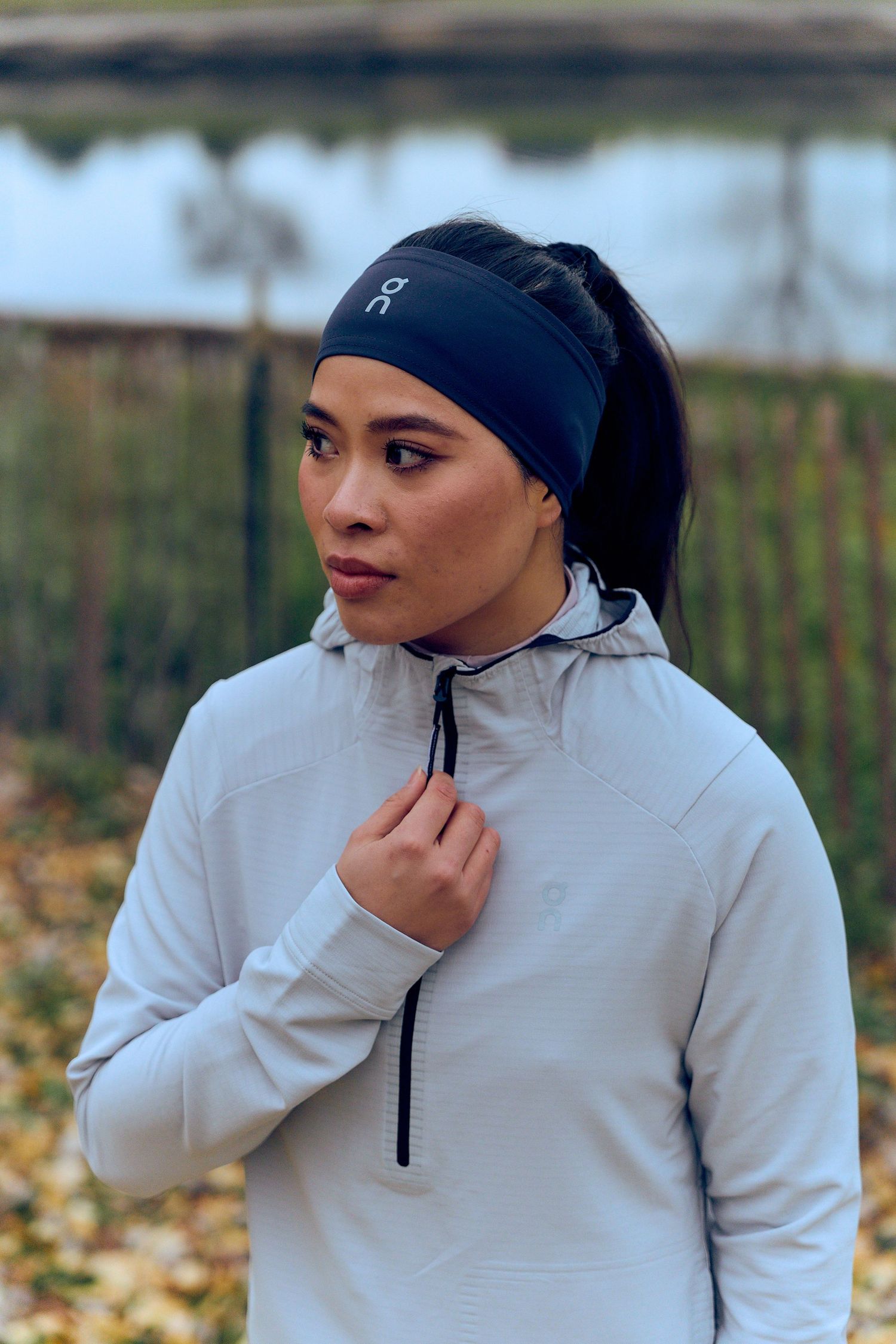 Athletic wear photoshoot featuring a cream-colored quarter-zip pullover and black beanie in autumn setting.