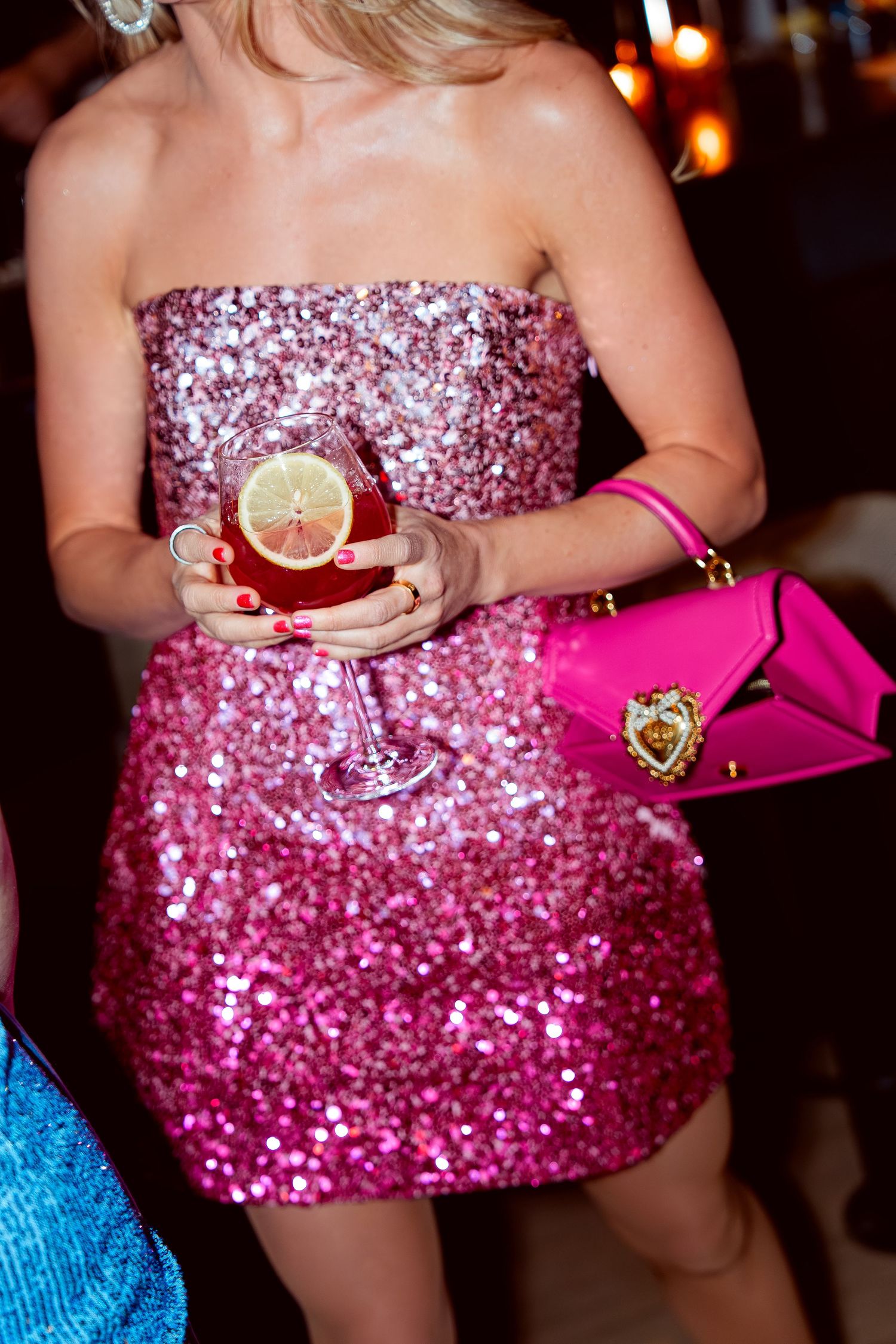 Close-up of sparkly pink cocktail dress with martini glass and pink designer purse.