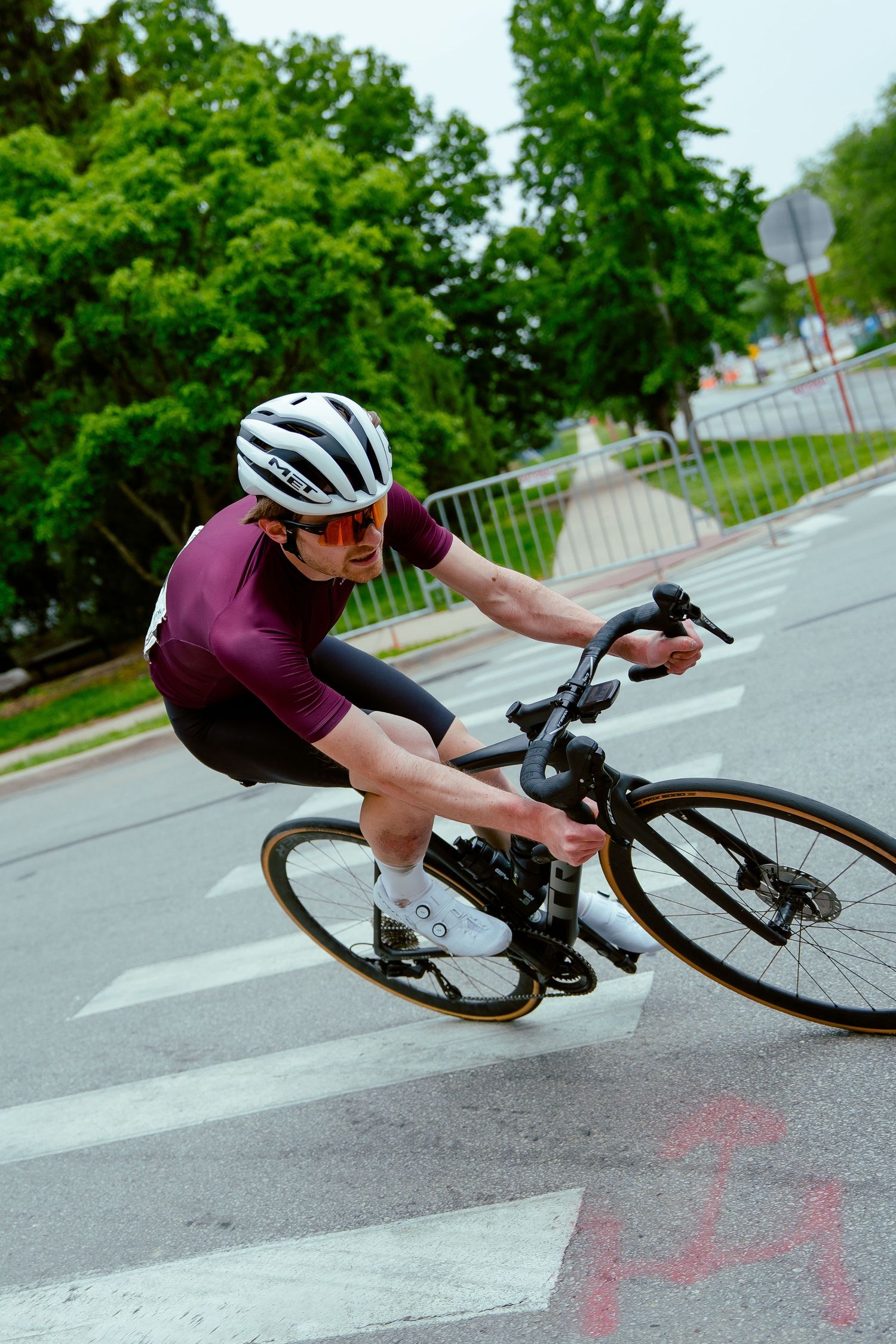 Cyclist in purple jersey leans into a sharp corner during a street race.