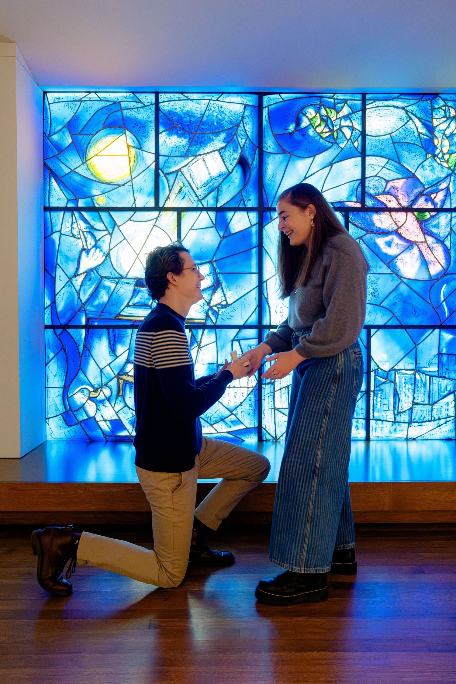Proposal moment captured against a beautiful blue stained glass window backdrop.