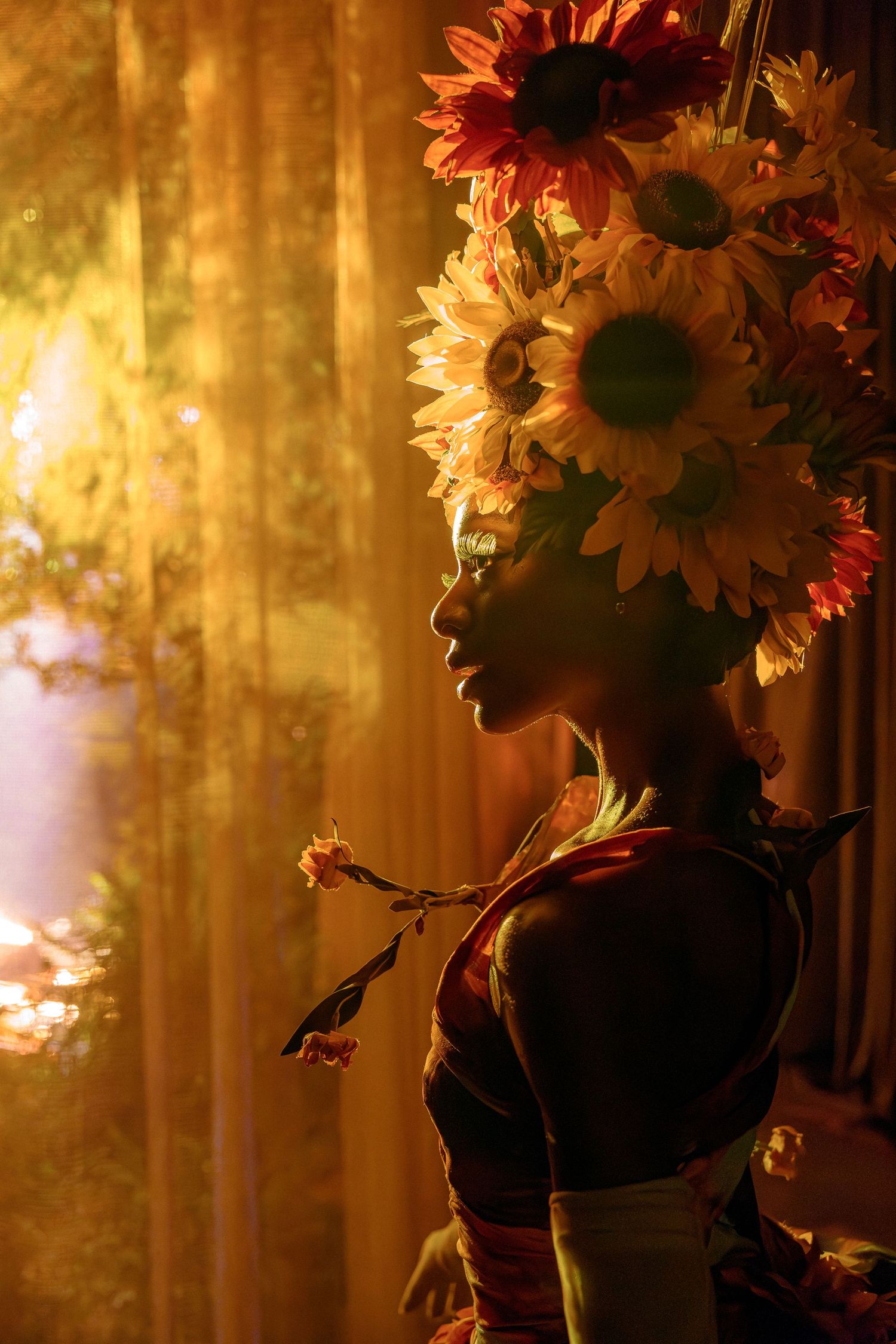 Ethereal silhouette with floral crown in golden backlight creates dramatic artistic effect.