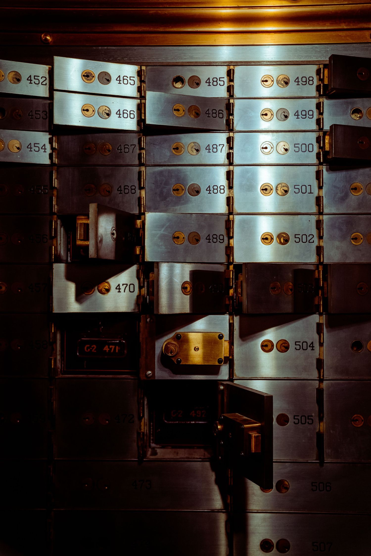Numbered safety deposit boxes in a dimly lit bank vault.