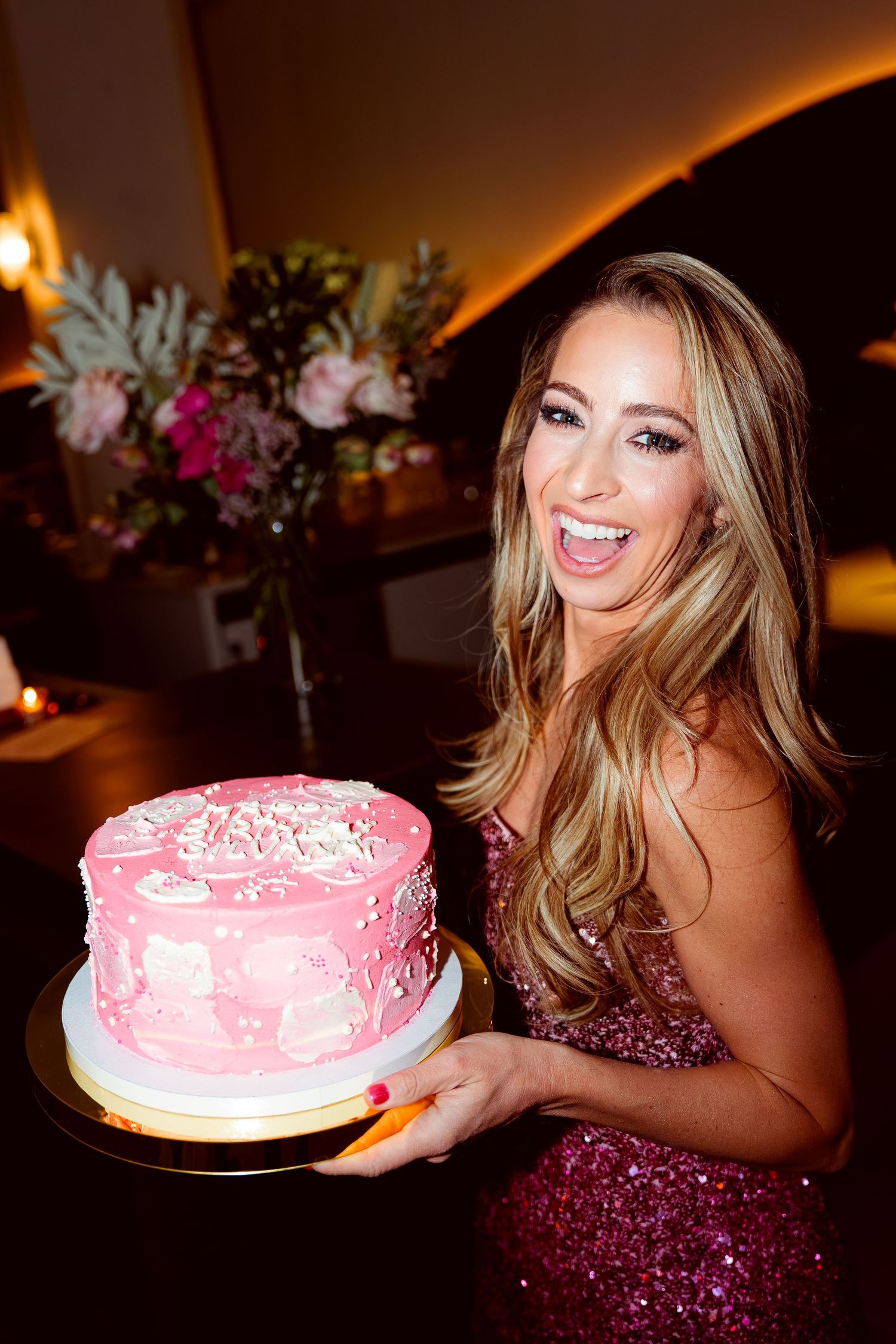 Sparkly pink celebration cake being presented at an elegant evening party.