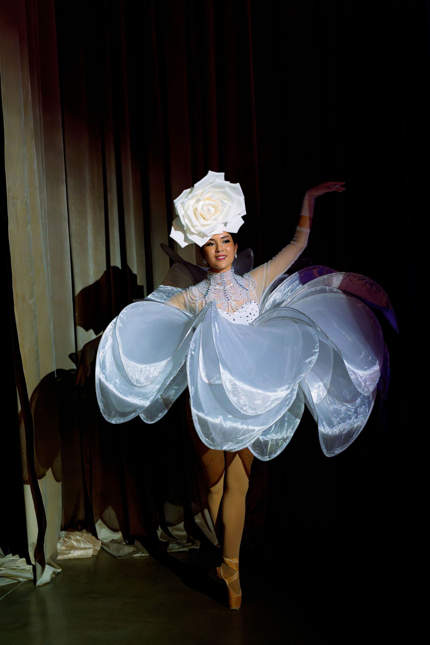 Performers in flowing white costumes dance gracefully on a darkened stage.