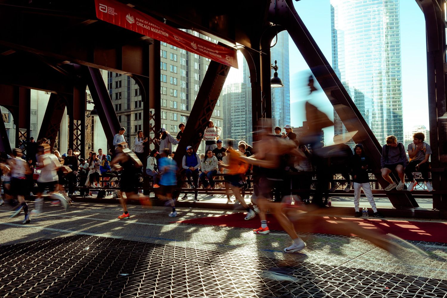 Silhouetted runners crossing a bridge during an urban marathon race.