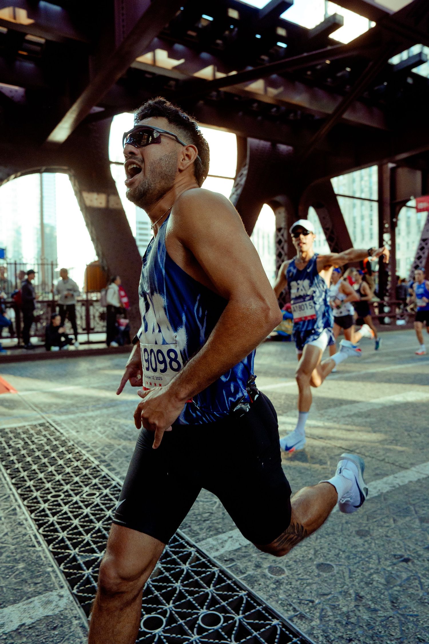 Energetic marathon runner in blue tank top racing through an urban course.