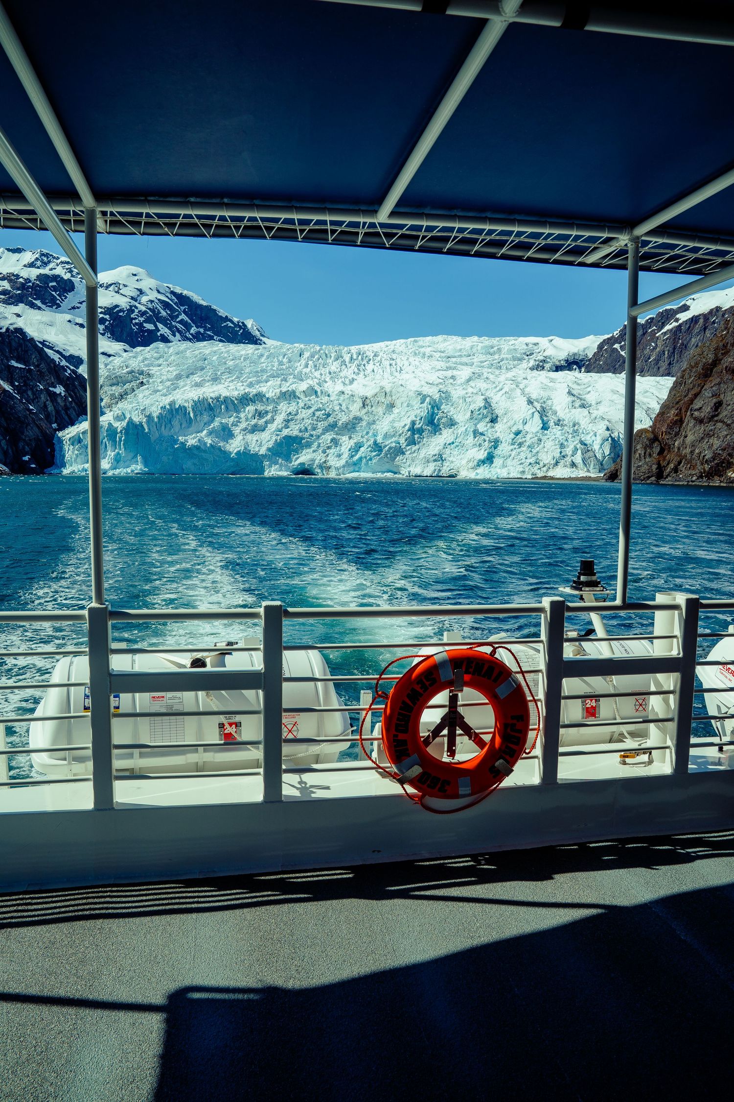 Glacier view from boat deck with orange life preserver ring in foreground.