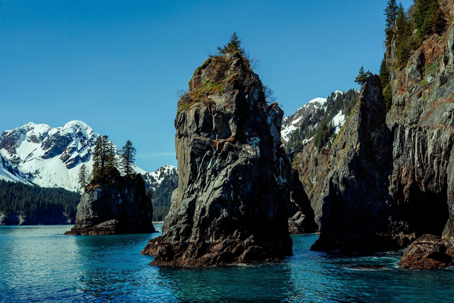 Rocky coastal cliffs and sea stacks rising from blue ocean waters.