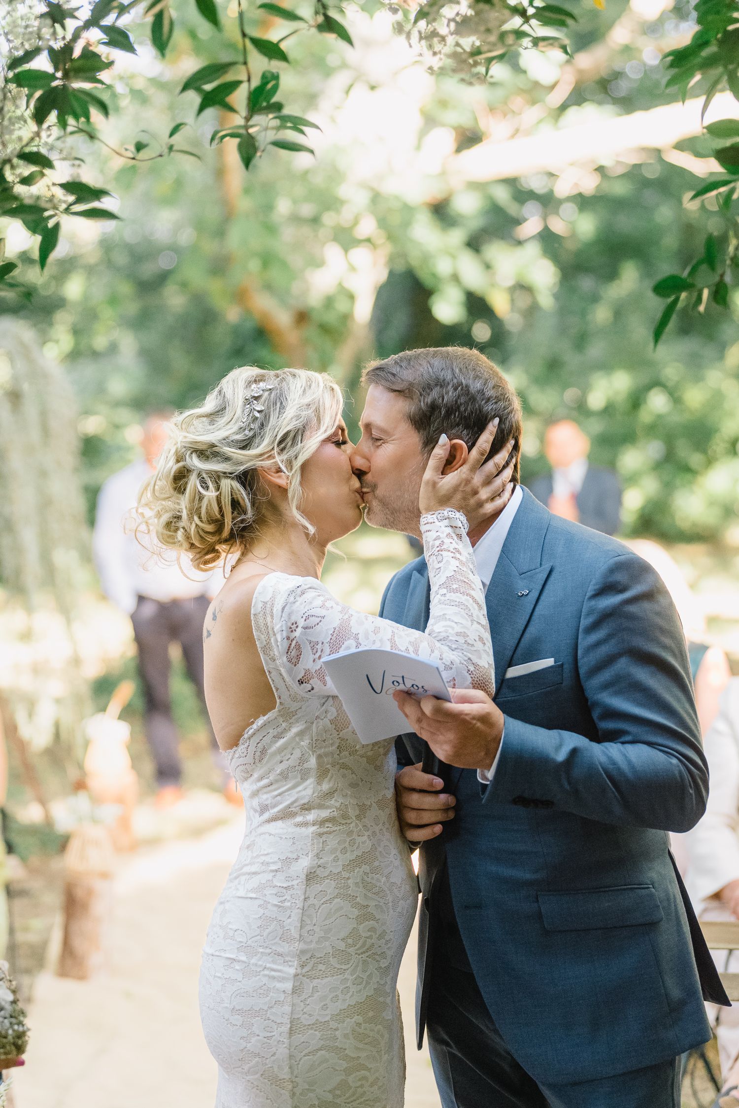 A romantic wedding couple shares an intimate kiss outdoors in a natural garden setting.