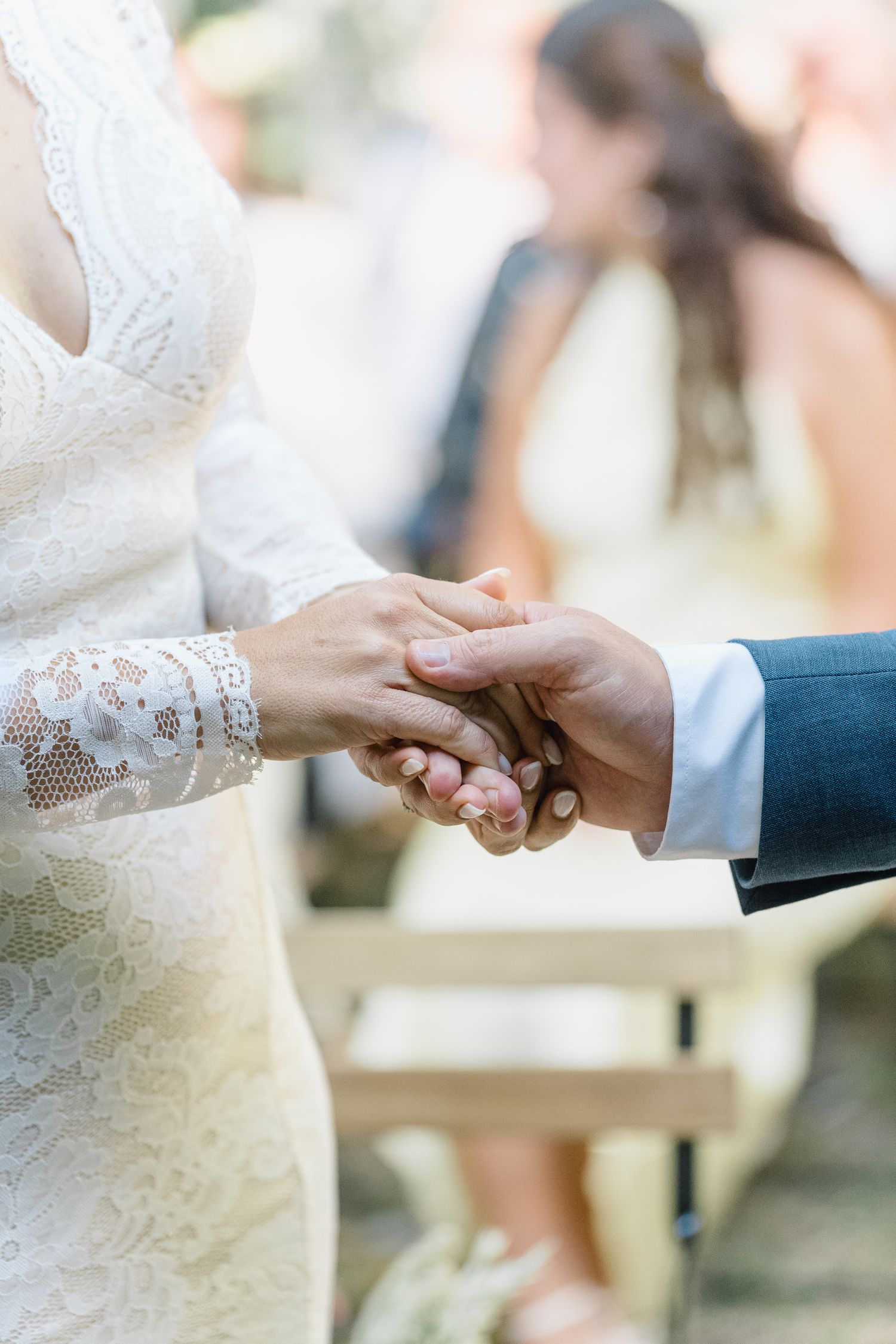 Close-up view of hands exchanging wedding rings during an outdoor ceremony against a soft blurred background.
