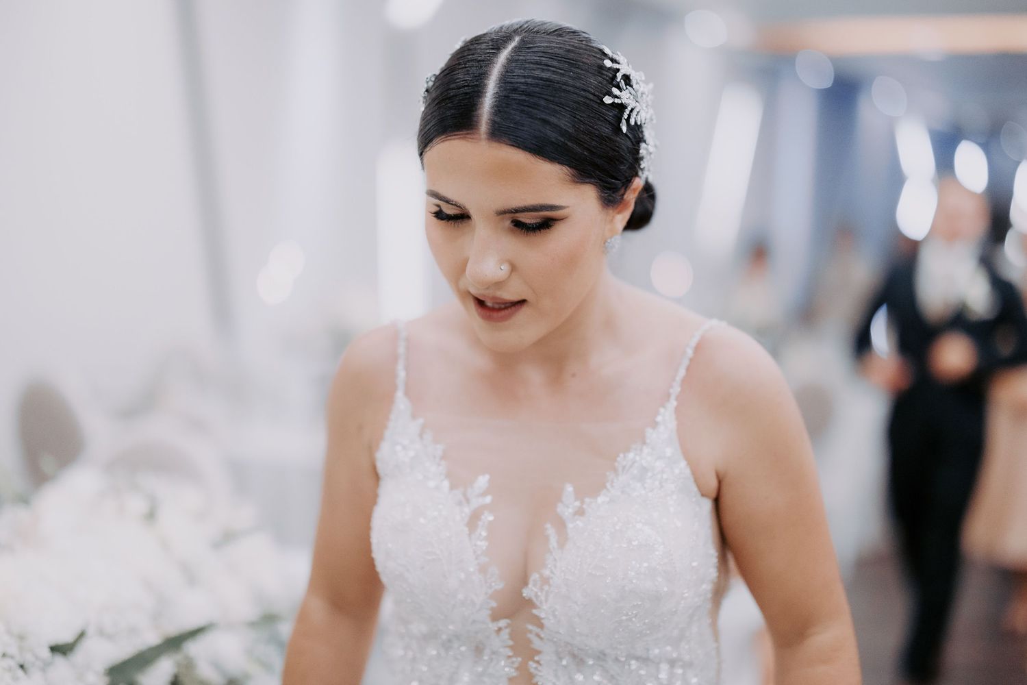 Bride wearing an elegant white lace wedding dress with sheer plunging neckline detail during wedding preparations.