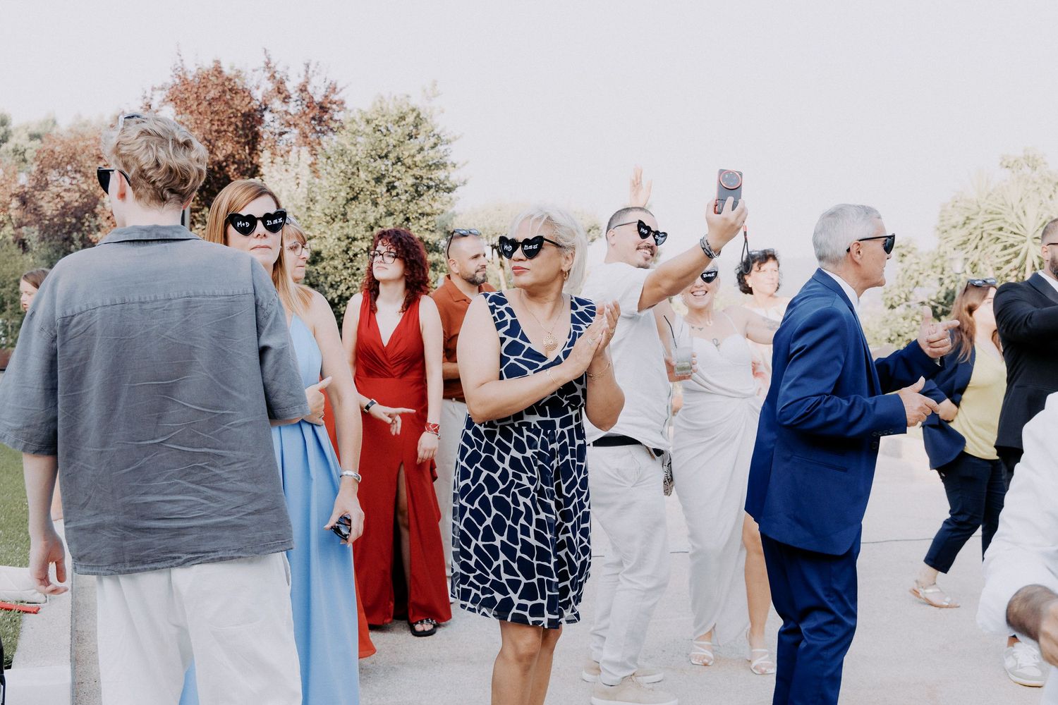Group of wedding guests dancing and celebrating together outdoors during a festive reception party.
