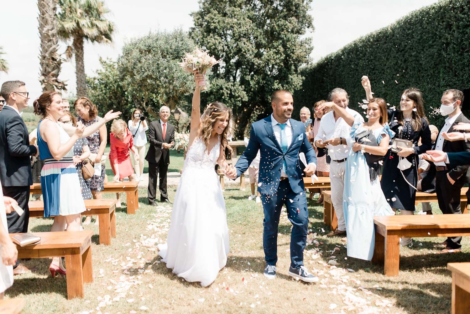Wedding guests celebrate with sparklers during an outdoor evening reception at a rustic venue with wooden benches.