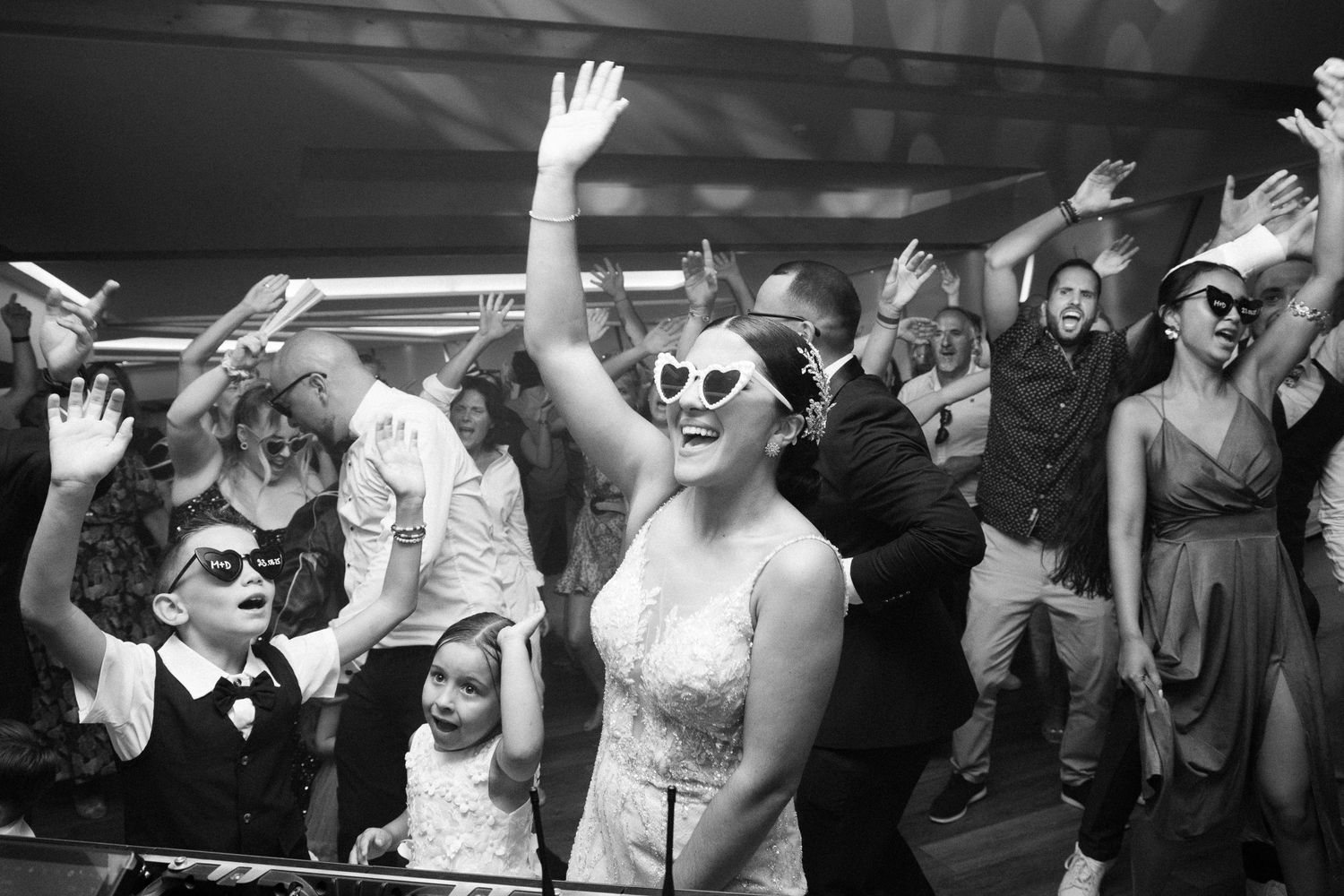 A group of people dancing and celebrating with raised hands at a party or event.