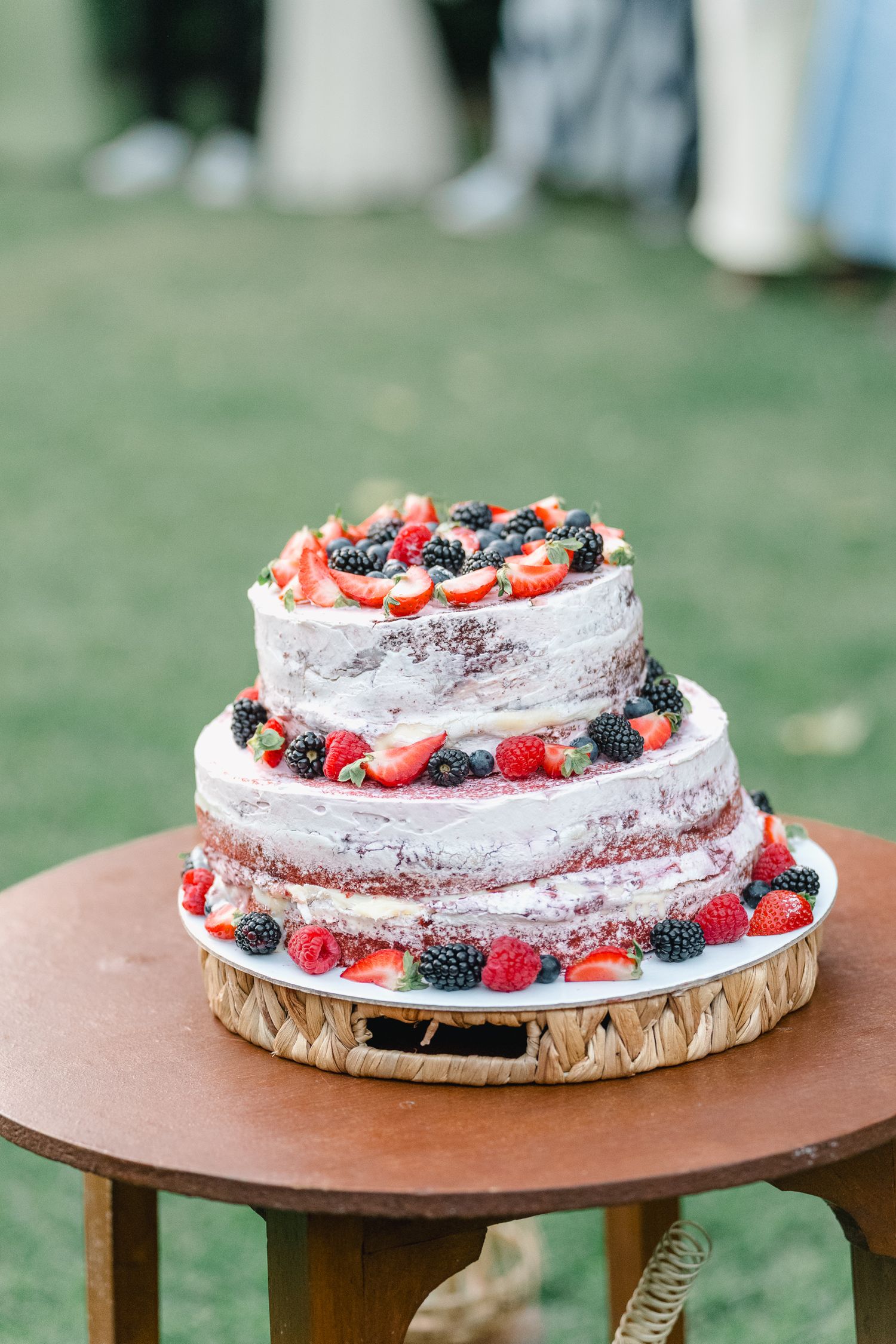 Bolo de casamento rustico decorado com frutos silvestres frescos em suporte de madeira. Casamento ao ar livre em ponte de lima