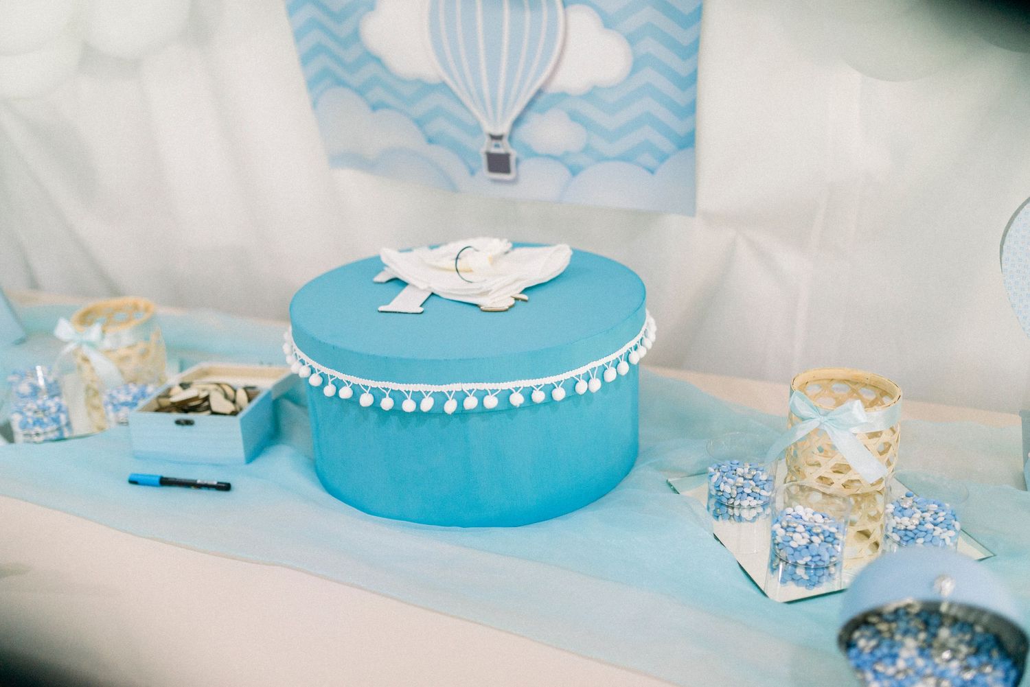 Blue and white themed baby shower decorations with cake, favors, and party supplies arranged on a table.