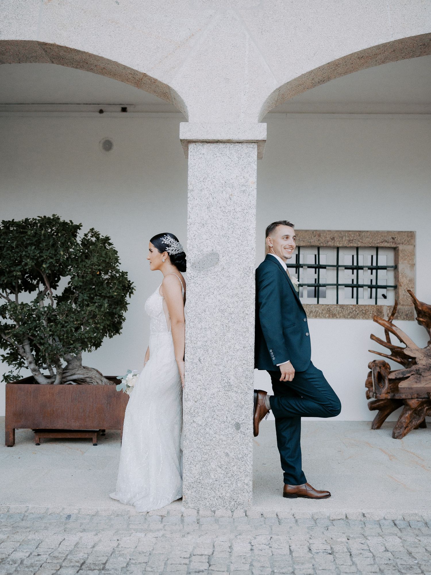 A series of wedding photos showing a couple in white dress and navy suit posing against white arched walls and rustic decor.
