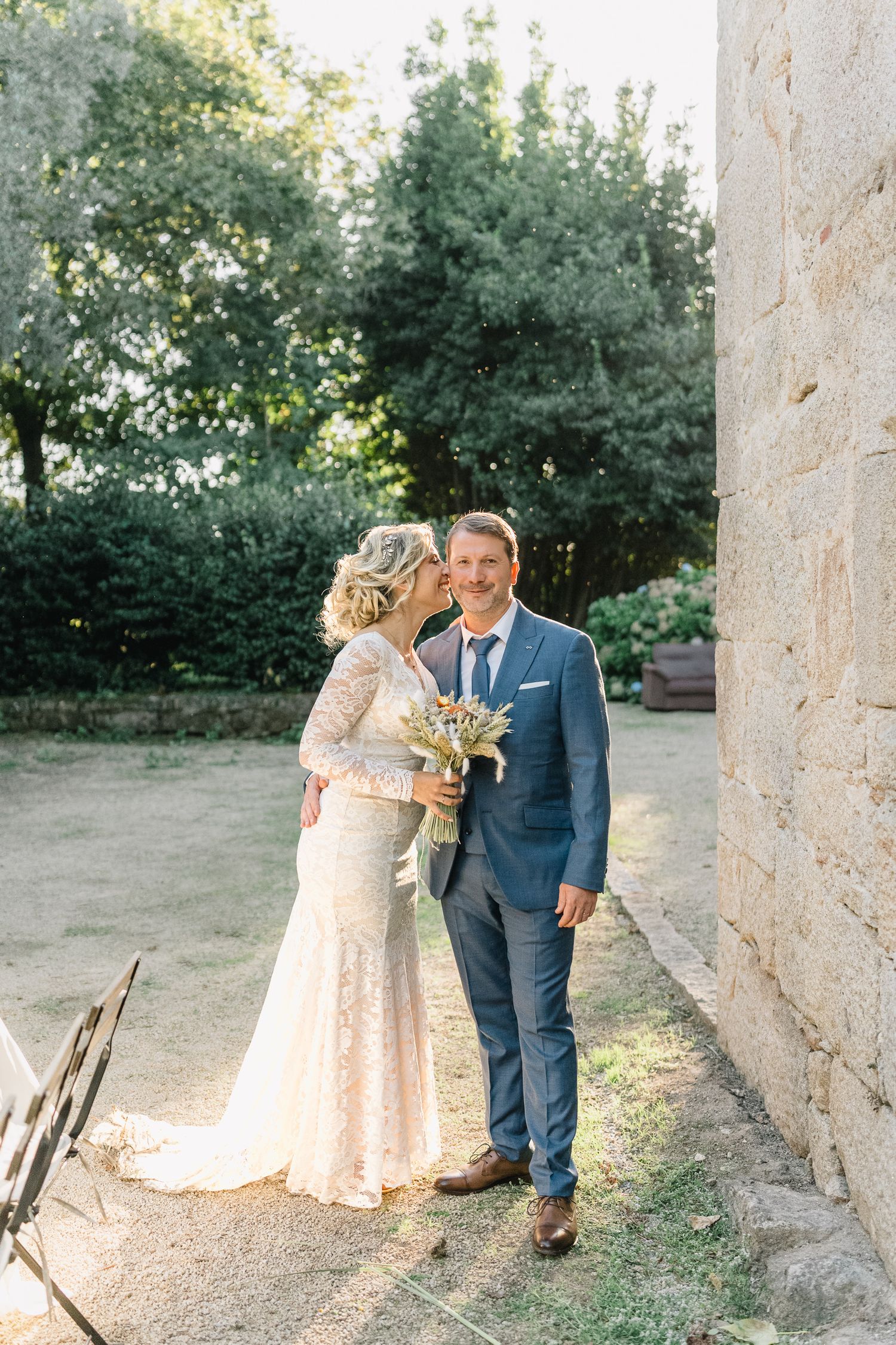 Um casal romântico partilha momentos ternos num jardim com pilares de pedra ao pôr do sol. Casamento em ponte de lima