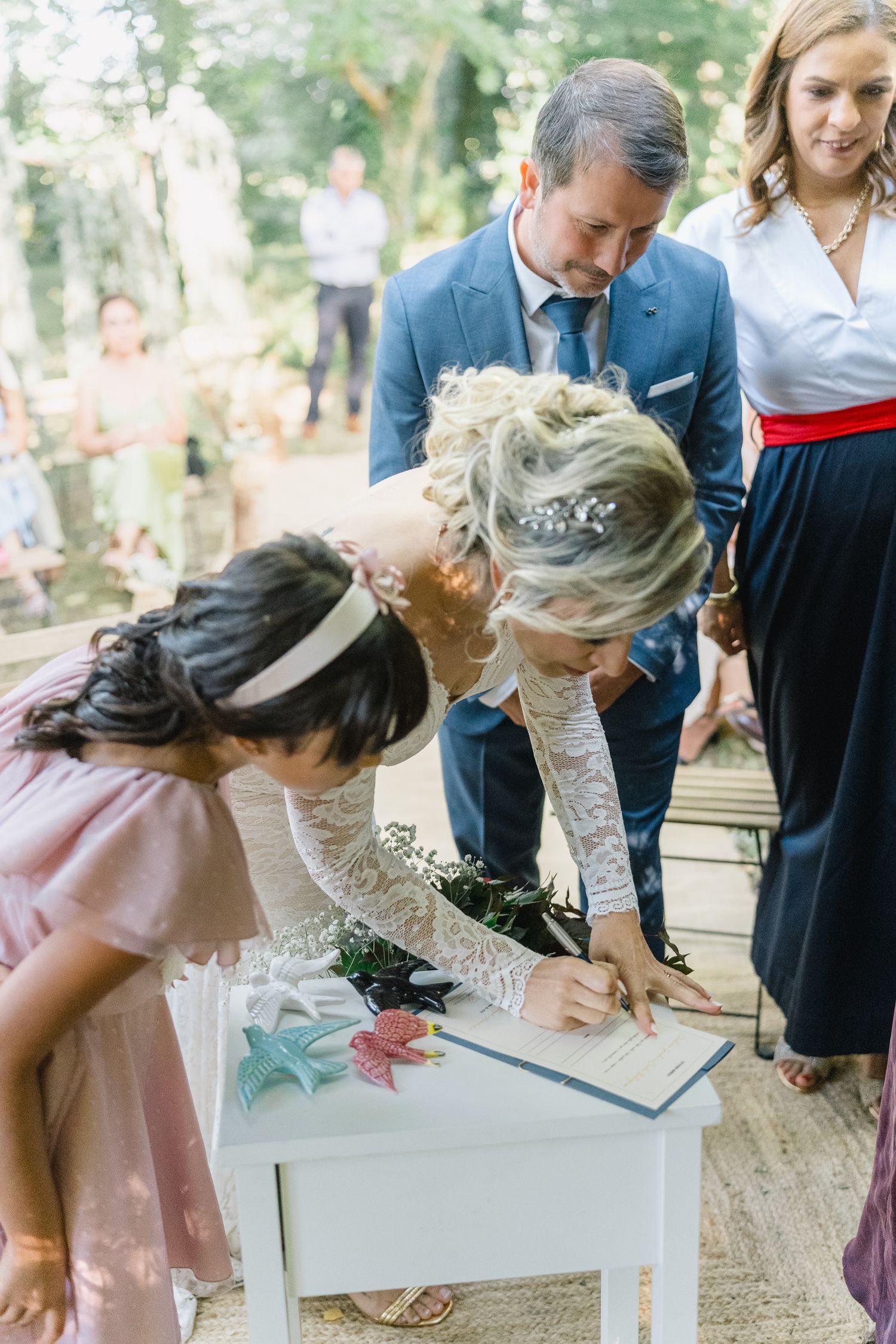 Os convidados do casamento assinam a certidão de casamento numa cerimónia de casamentoao ar livre enquanto outros assistem.